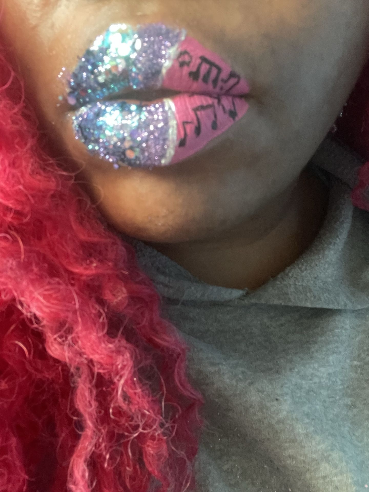 Black woman with silver glitter lip art and deep pink curls, close-up portrait featuring bold color contrast and editorial beauty styling