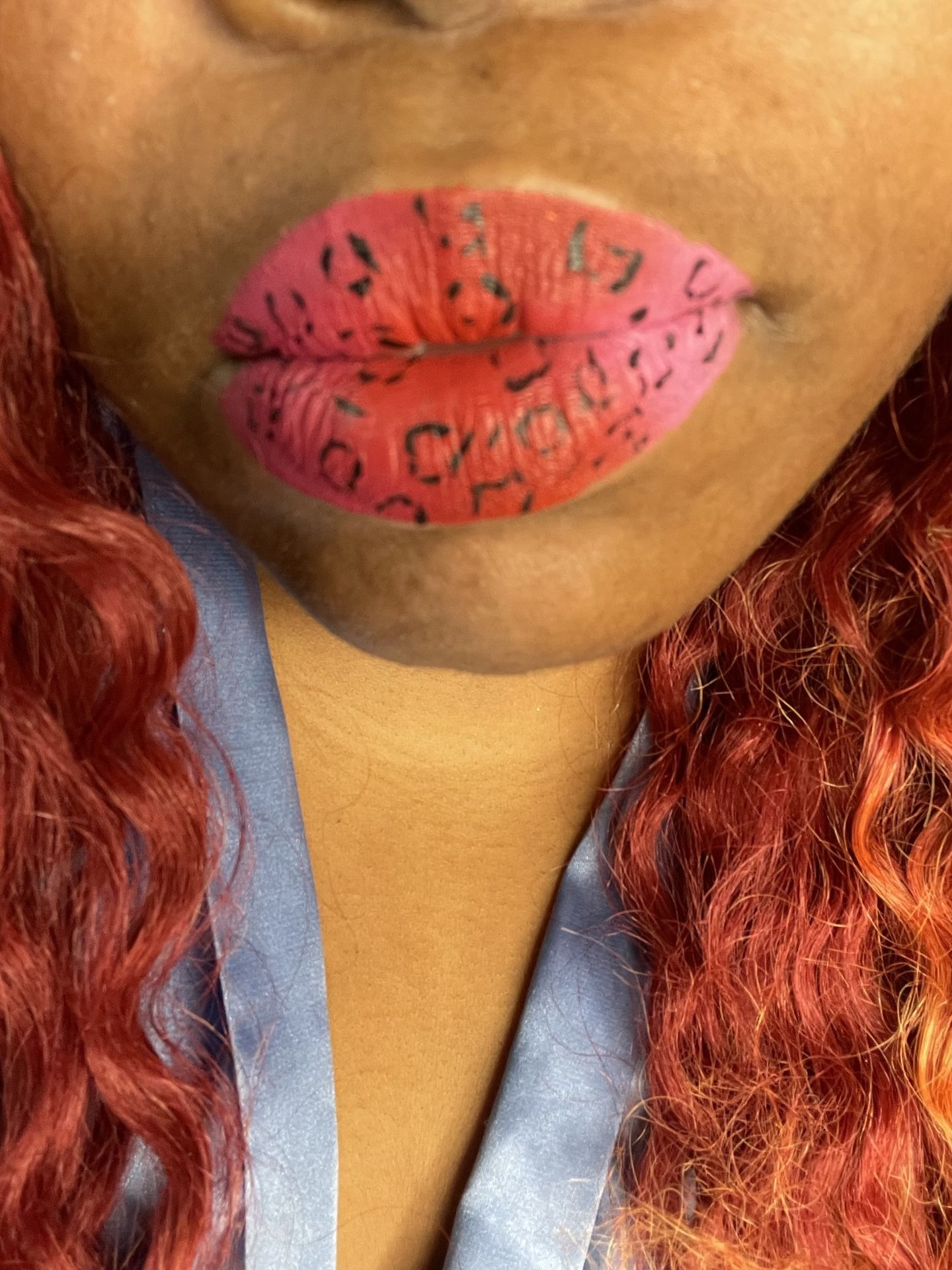 Black woman with red lipstick and textured gold shimmer detail, close-up beauty portrait highlighting bold color and artistic lip design