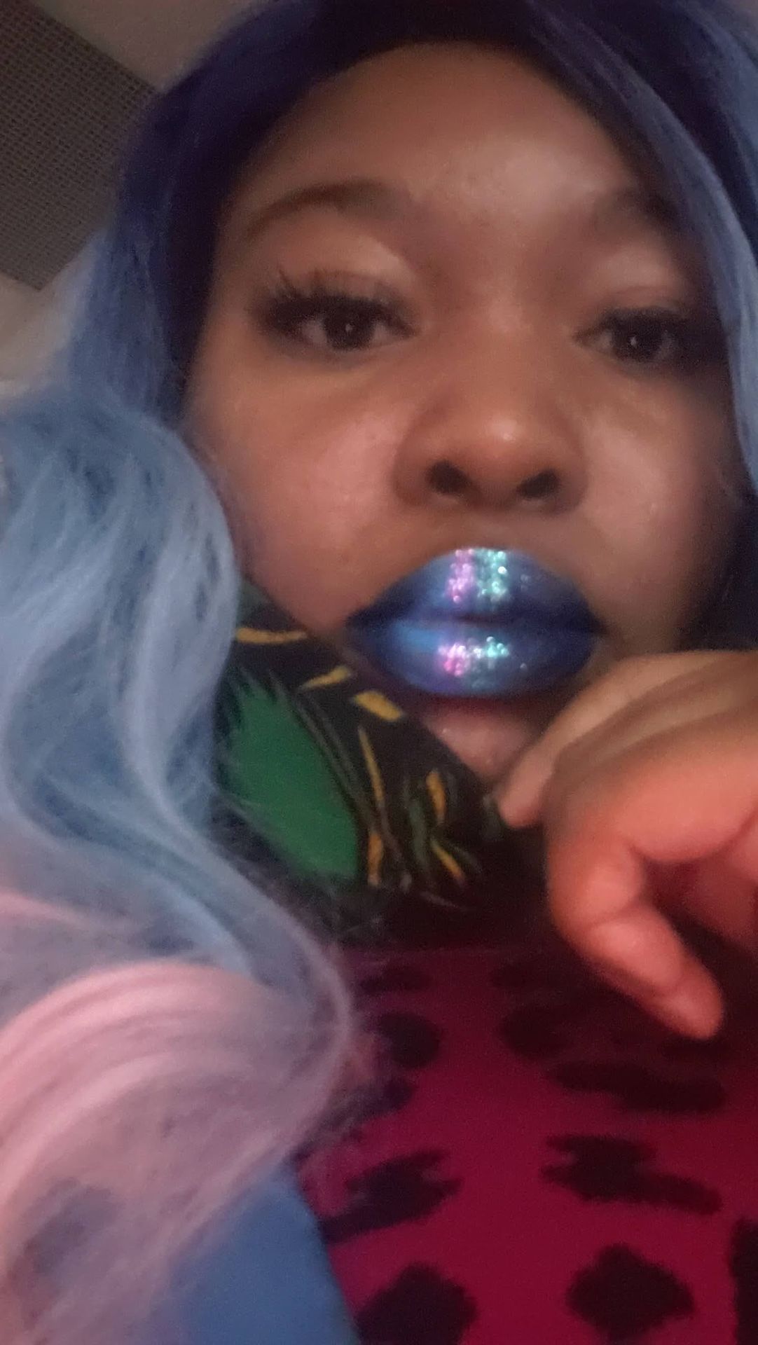 Close-up of glossy navy lipstick with green accent jewel at center