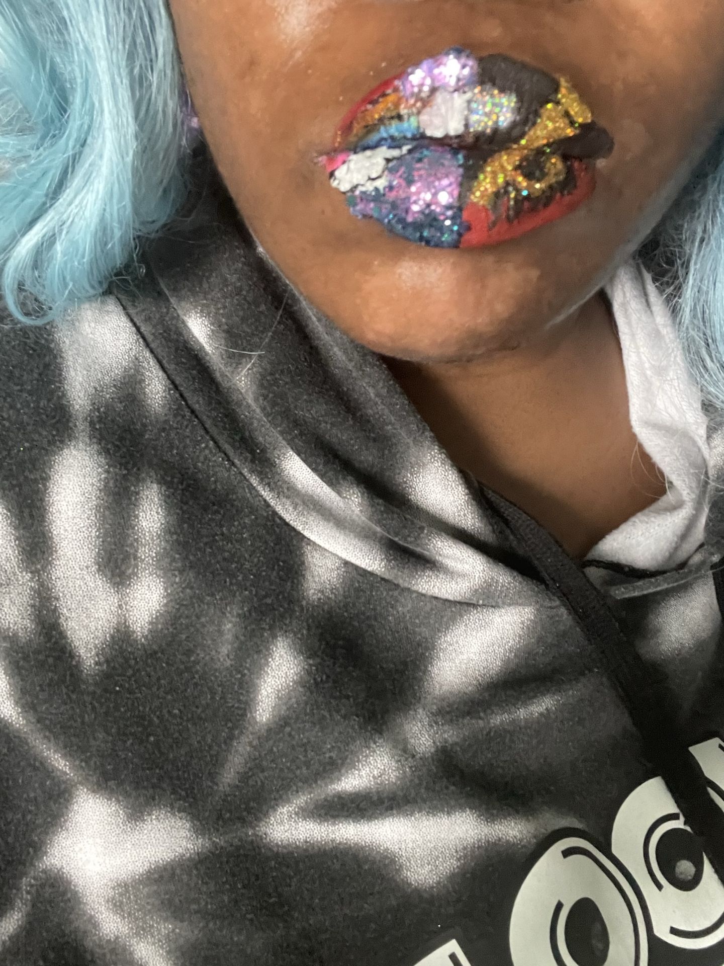 Black woman with lavender hair and holographic blue lip design, creative fashion close-up.