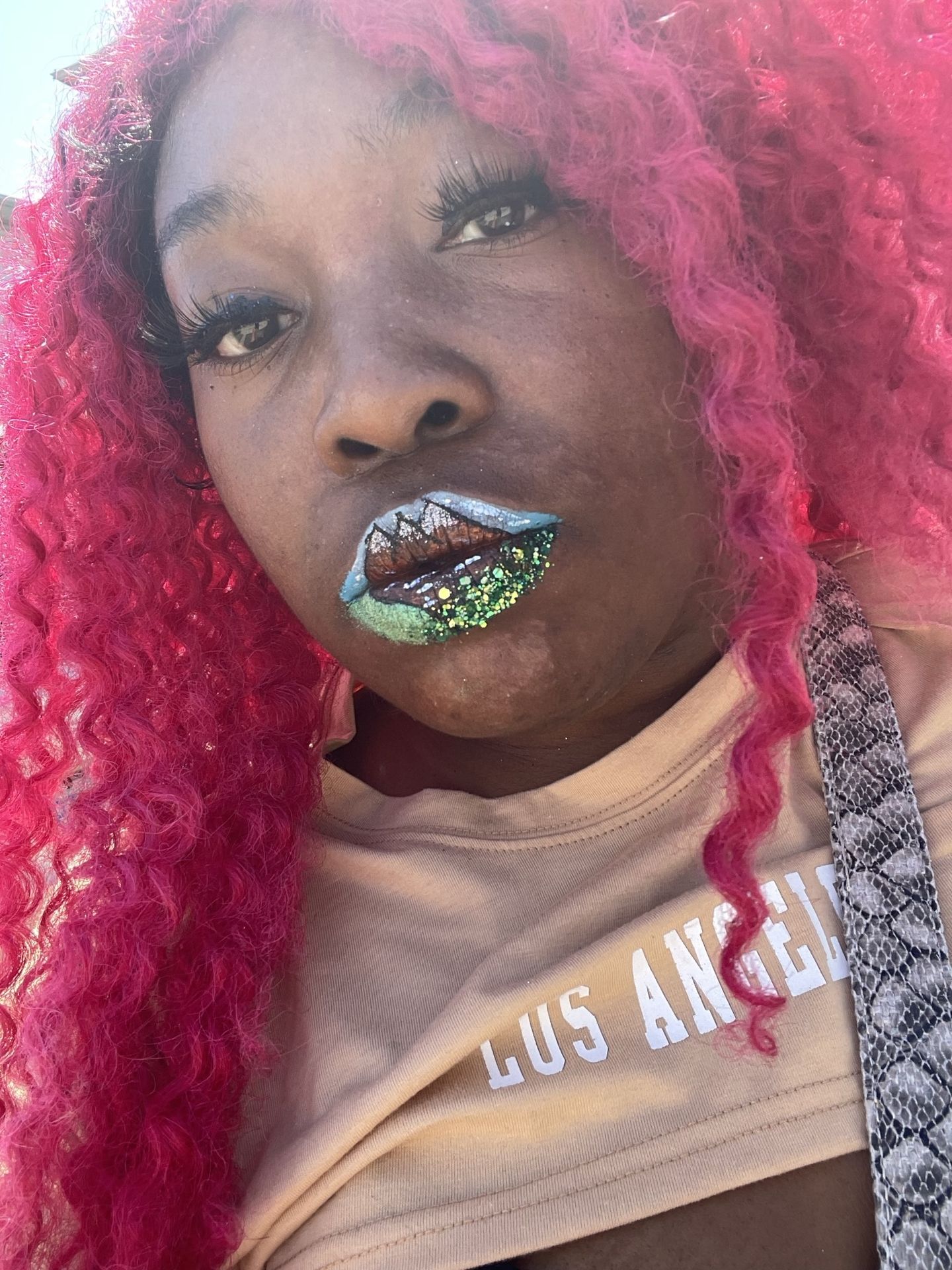 “Close-up of woman with pink braids and green mountain lip design.”