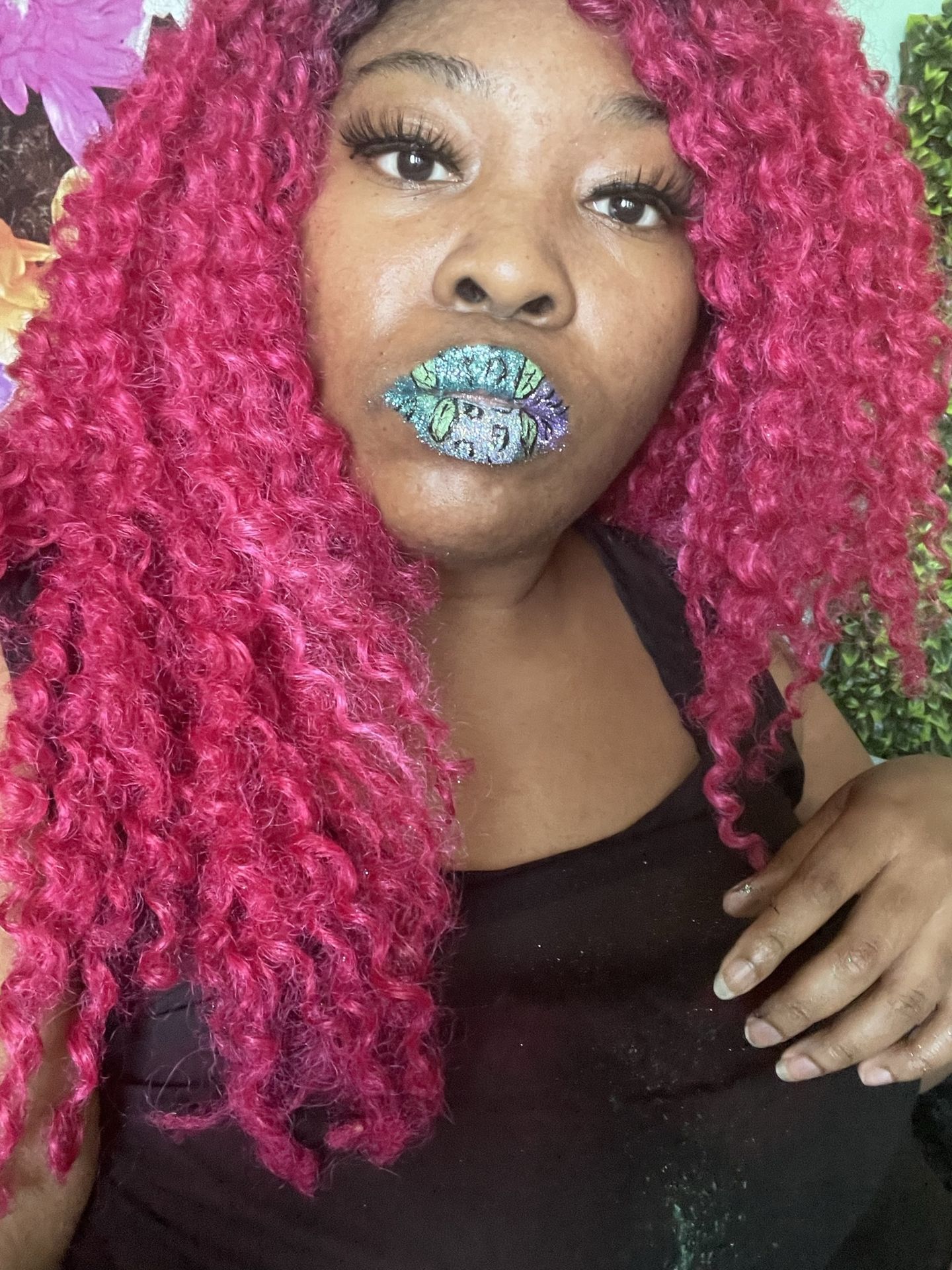 “Close-up of woman with pink braids and rhinestone lip makeup.”
