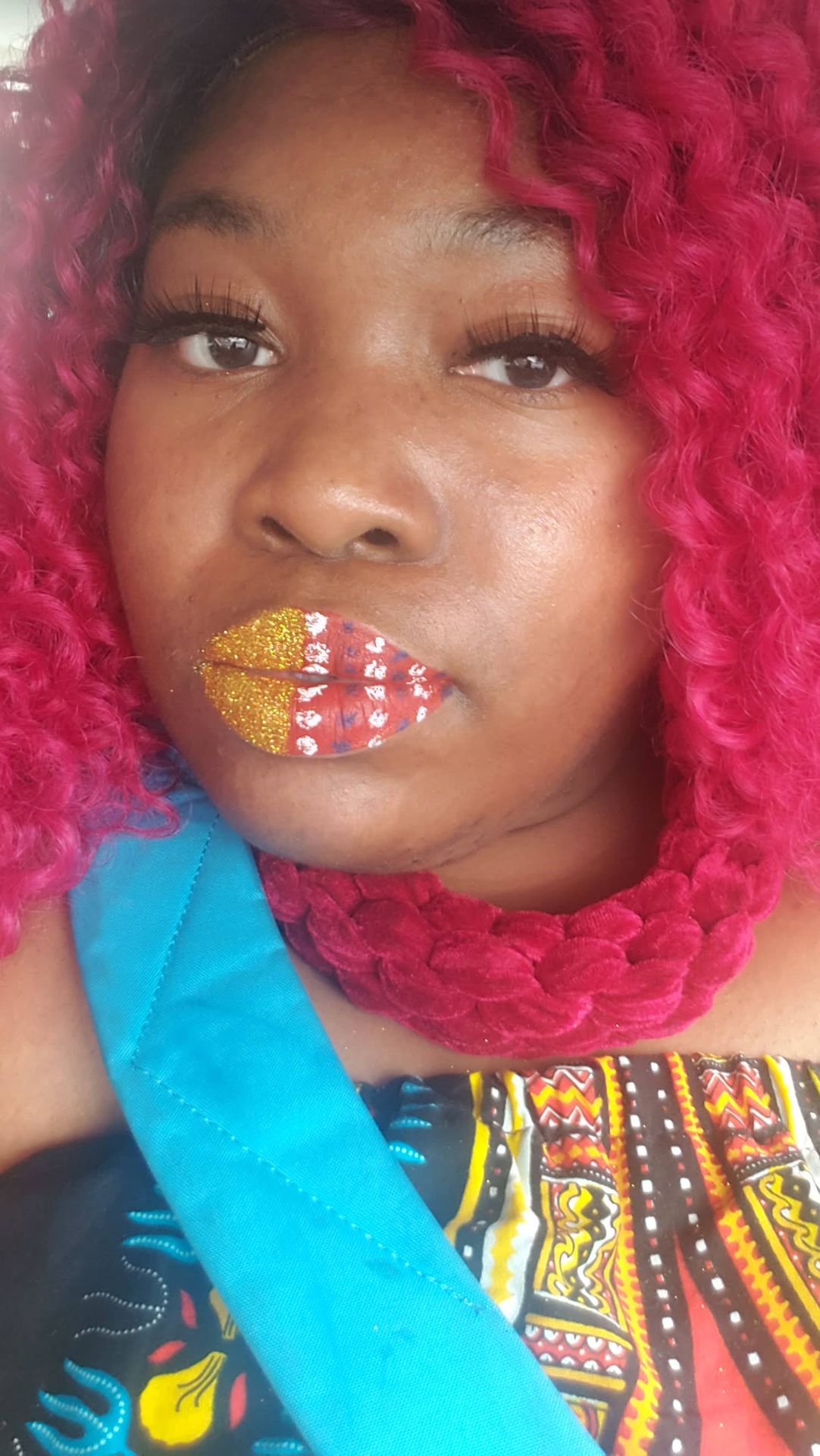 Woman with red curls wearing gold foil and coral-toned mosaic lips