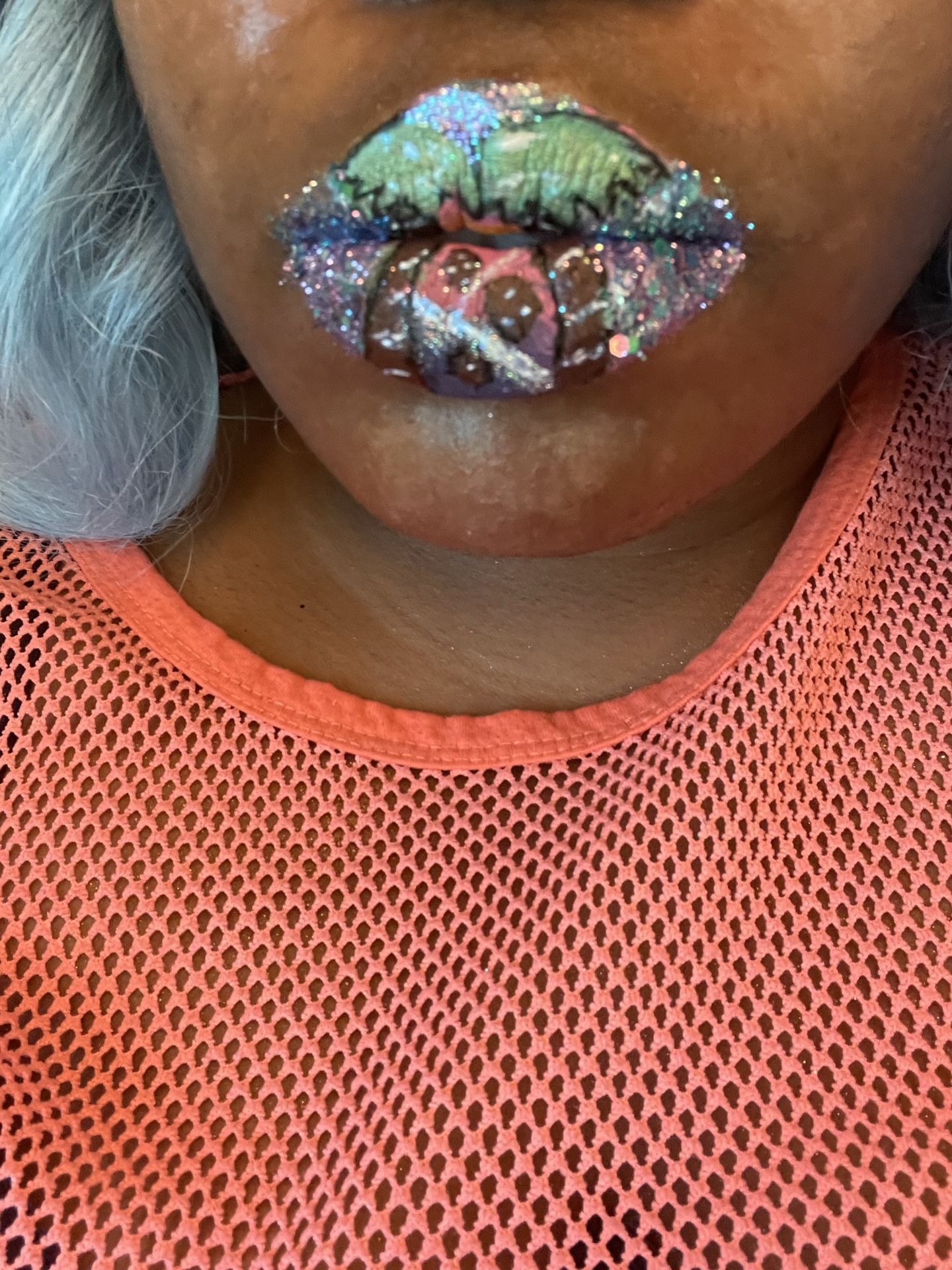 “Close-up of glitter-covered lips on woman wearing an orange sweater.”