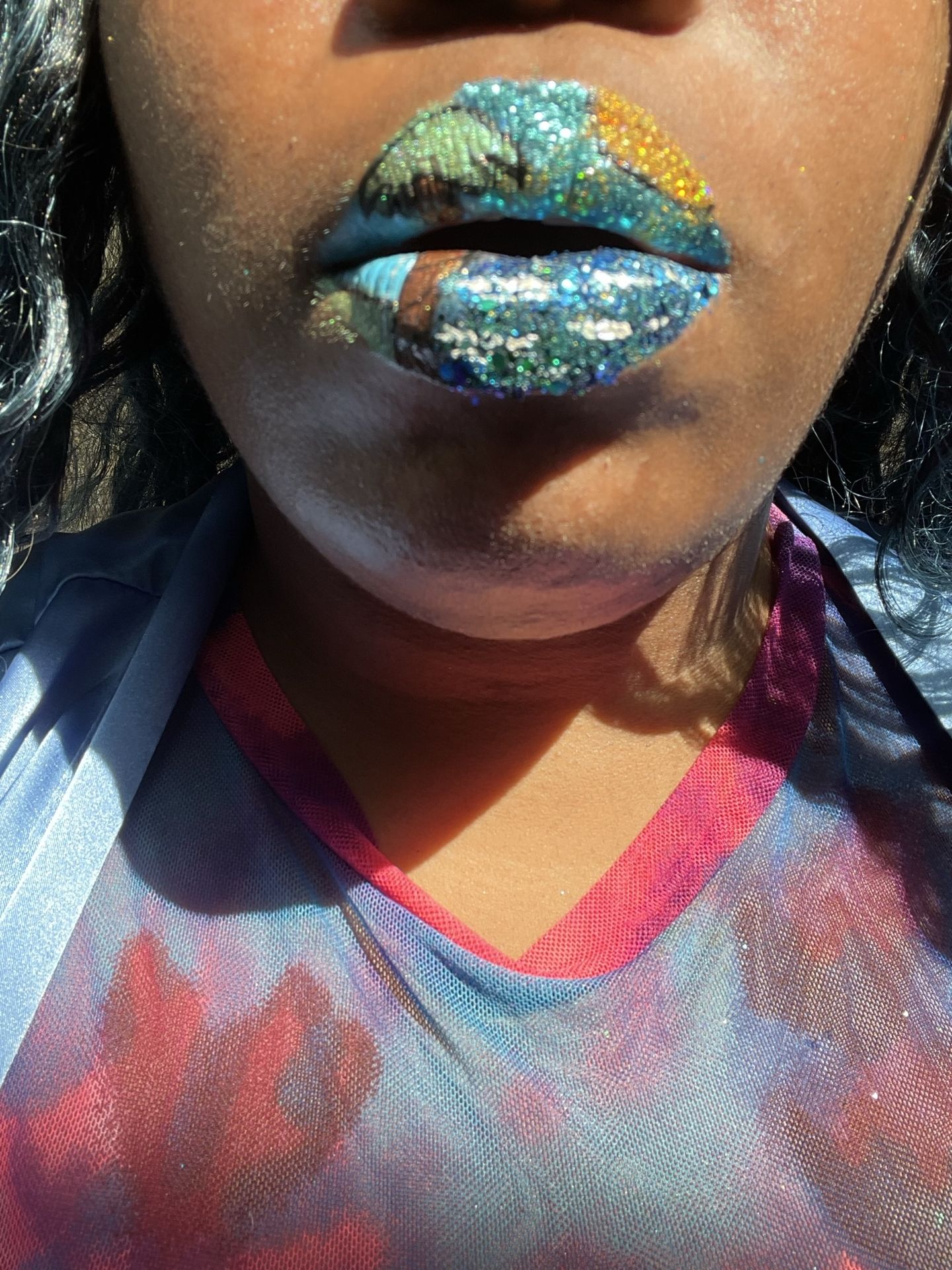 “Close-up of woman with blue and gold metallic lip art.”