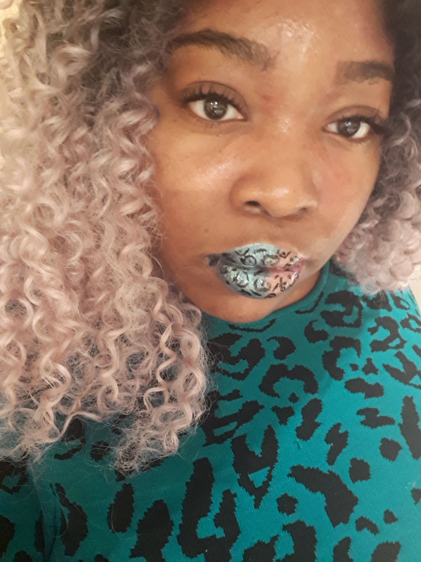 Woman with blonde curls wearing sea-green metallic lipstick