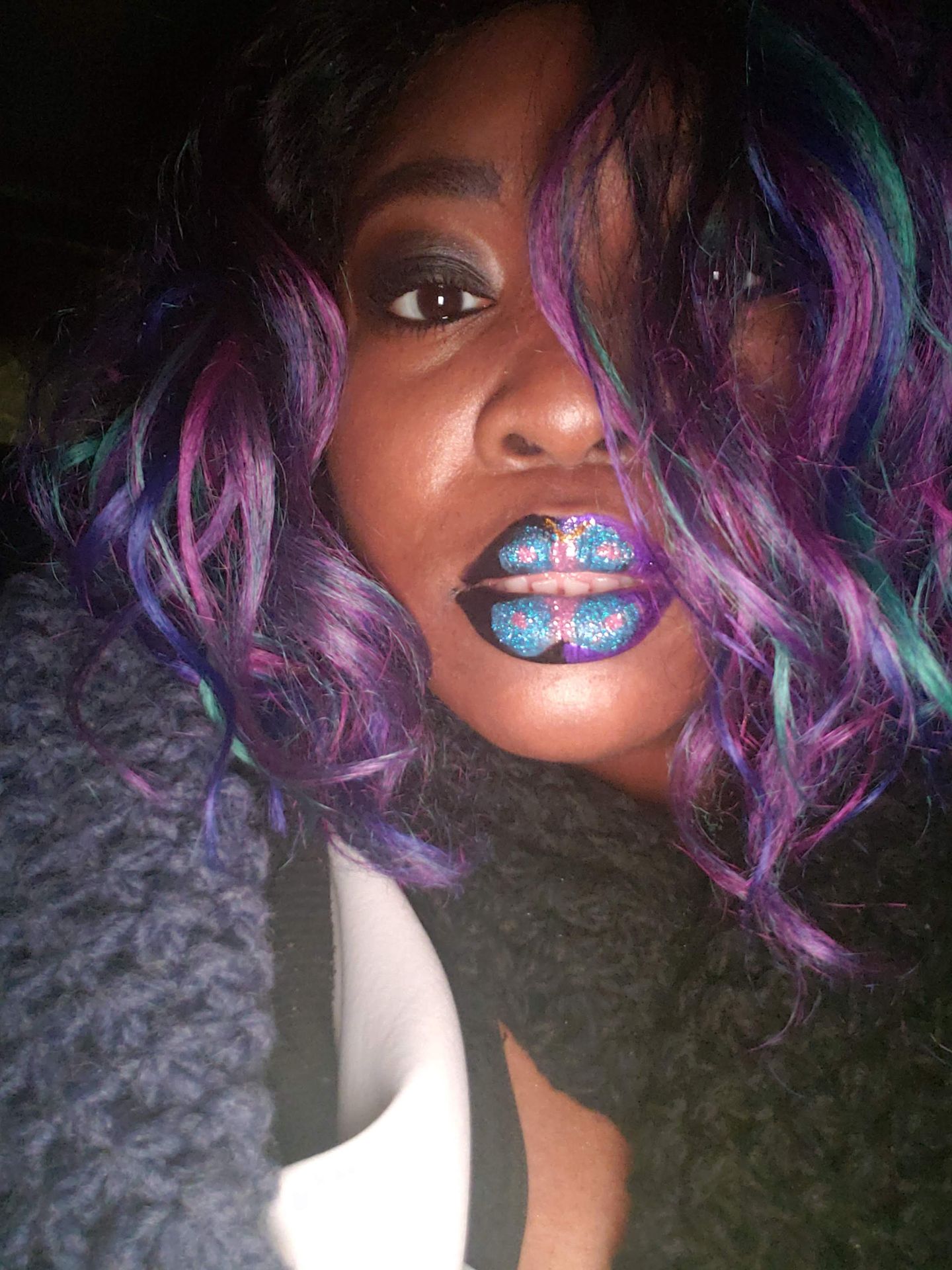 Woman with purple curls wearing electric cobalt glitter lipstick
