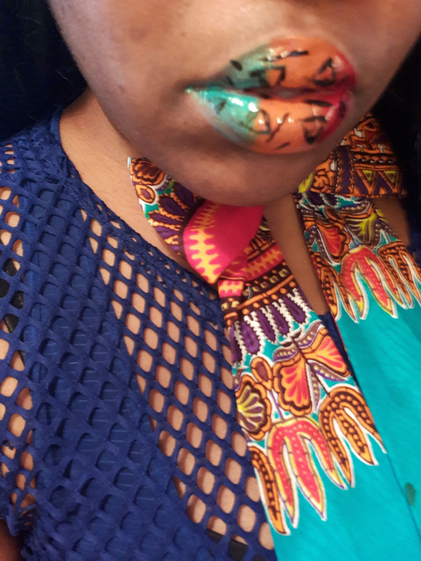 Close-up of multitone glitter lips with patterned fabric and gold chain