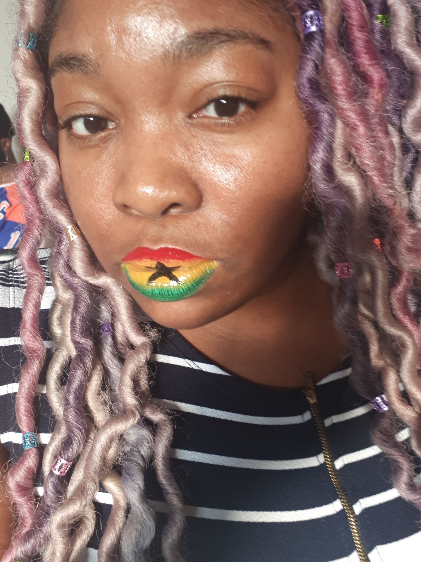 Black woman with lilac locs and neon green rhinestone lip accents