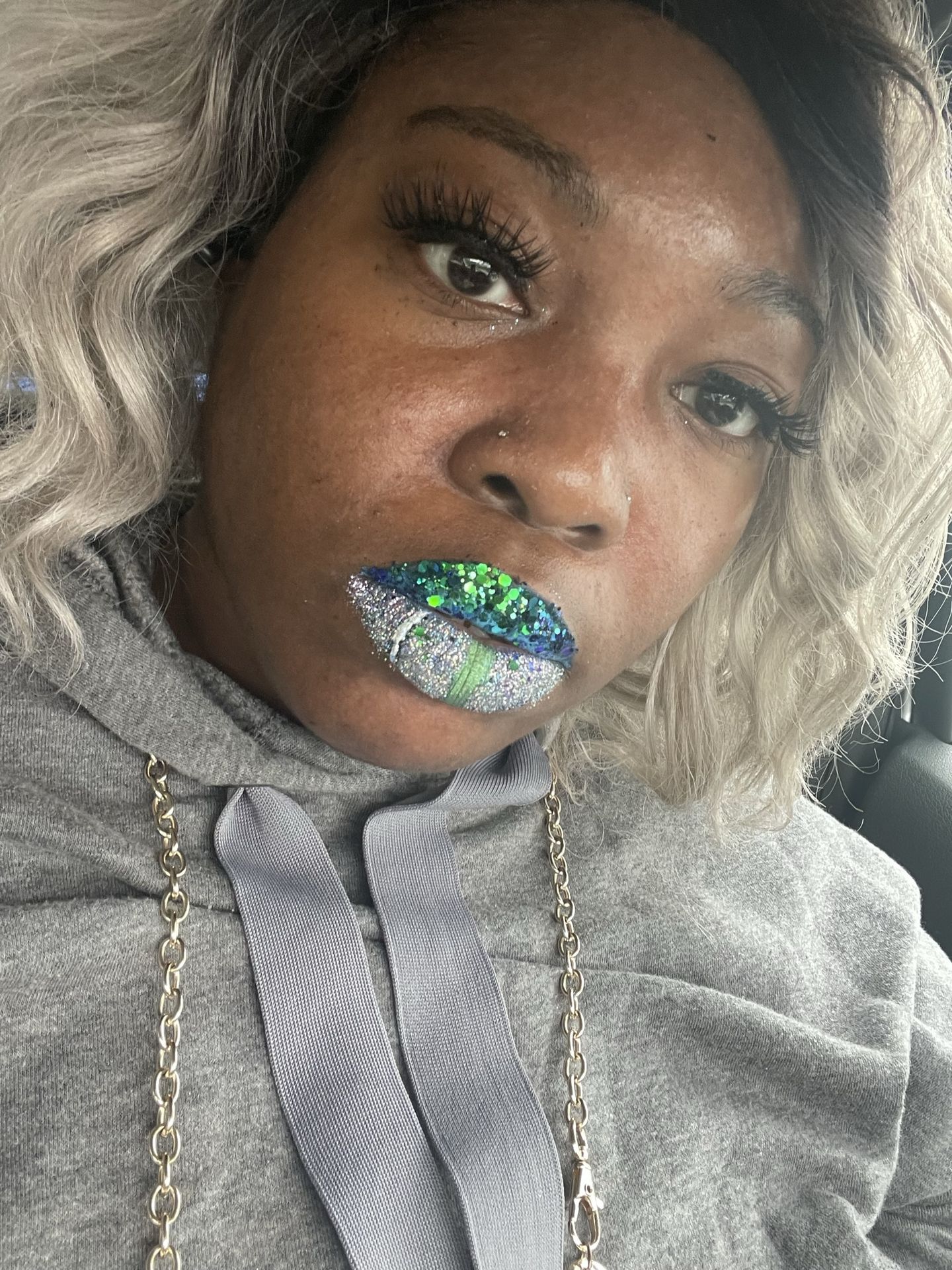 Black woman with silver wig and holographic blue lips, futuristic artistic makeup close-up.