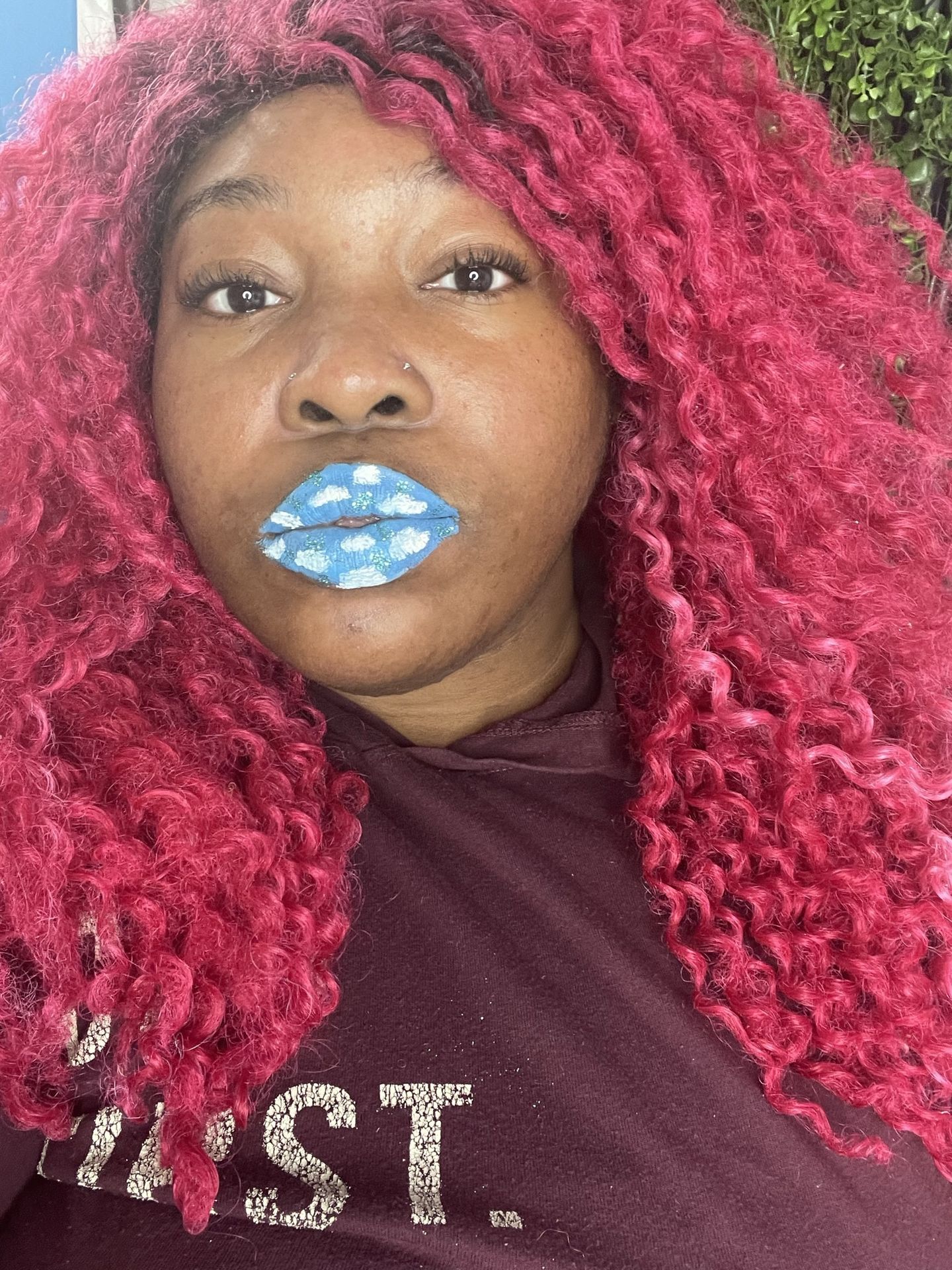 Woman with bright red curls wearing icy blue metallic lipstick