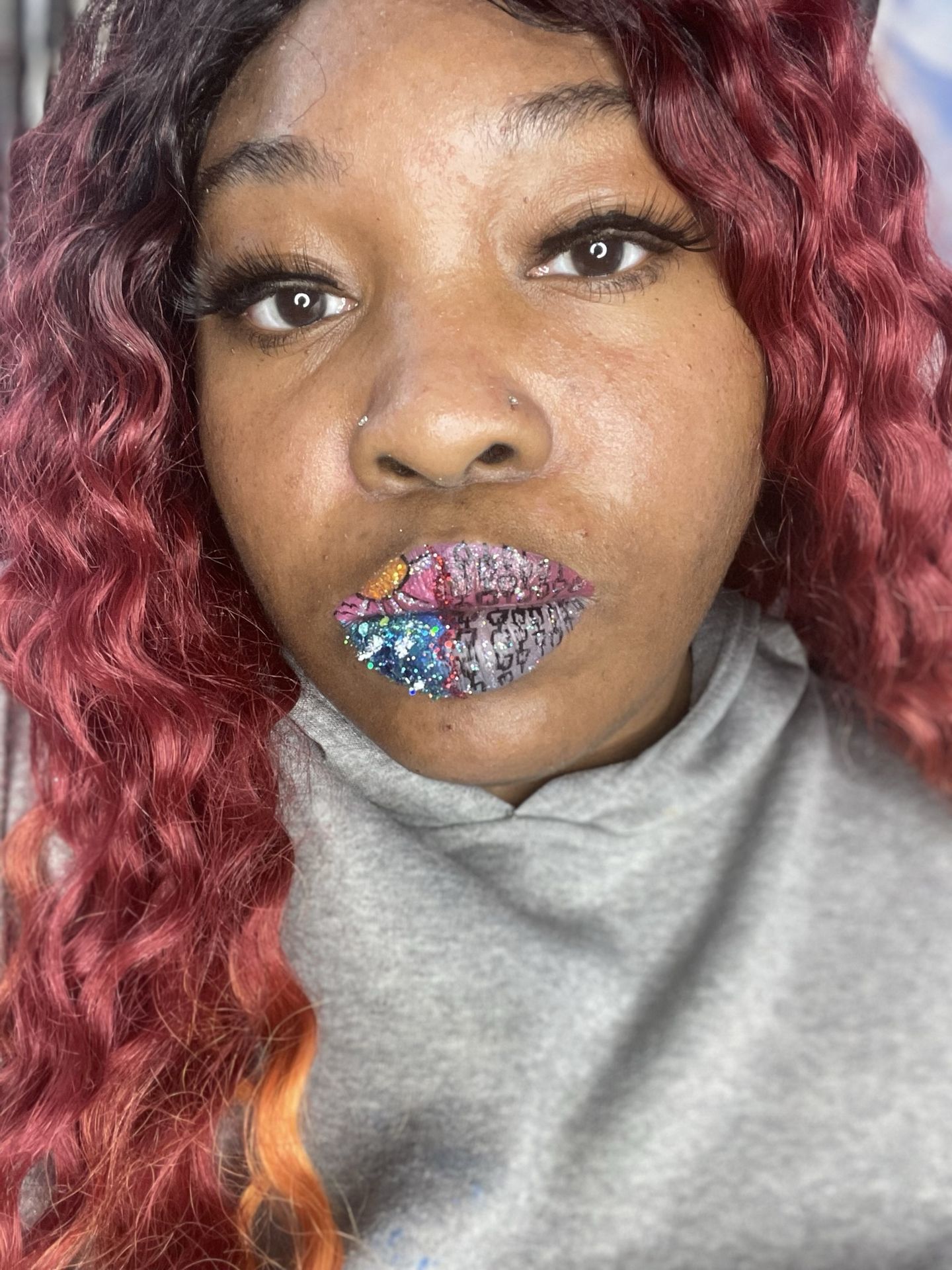 Woman with burgundy curls wearing iridescent gem-set lipstick