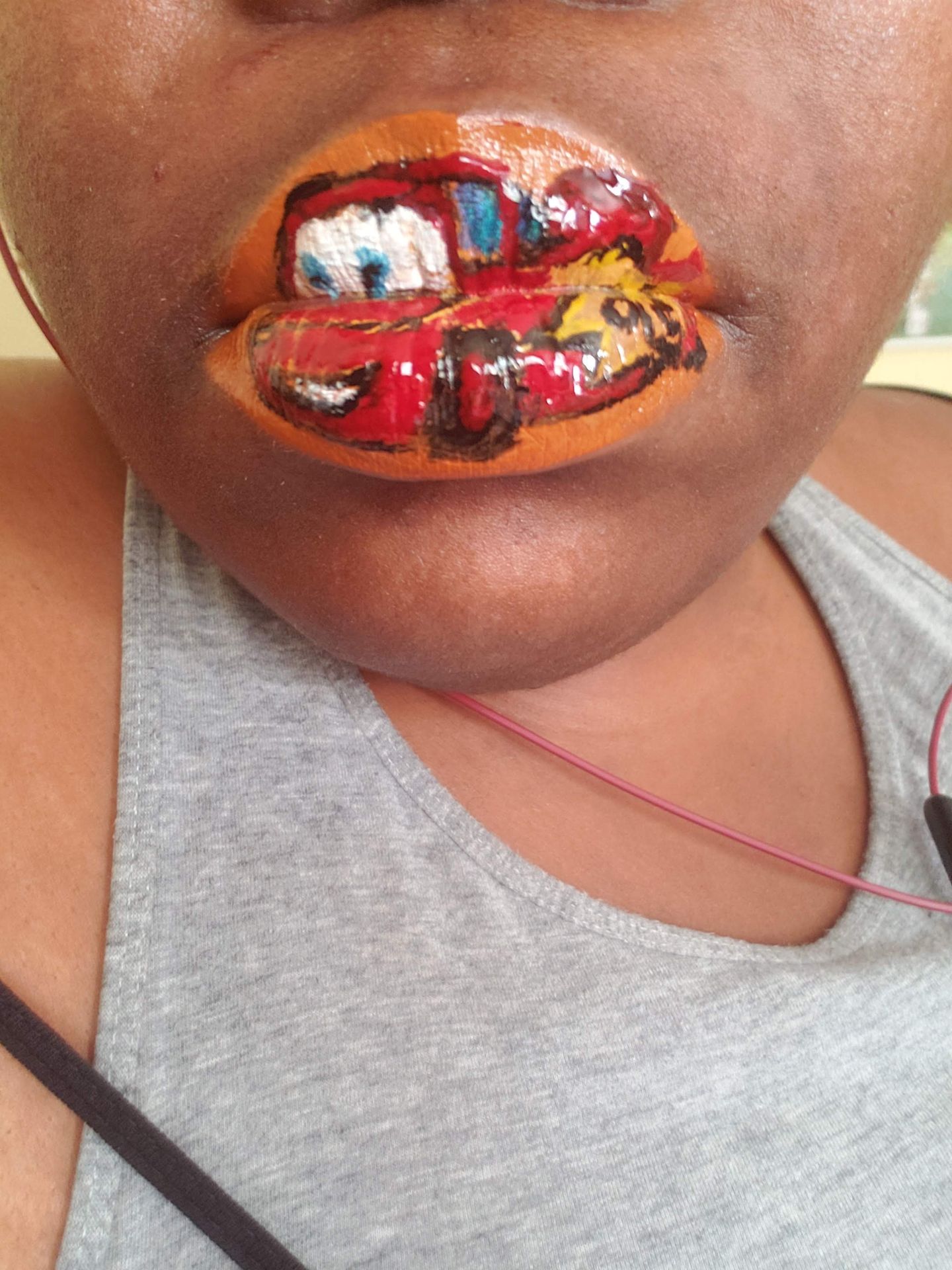 Close-up of lips covered in red, gold, and black rhinestone mosaic