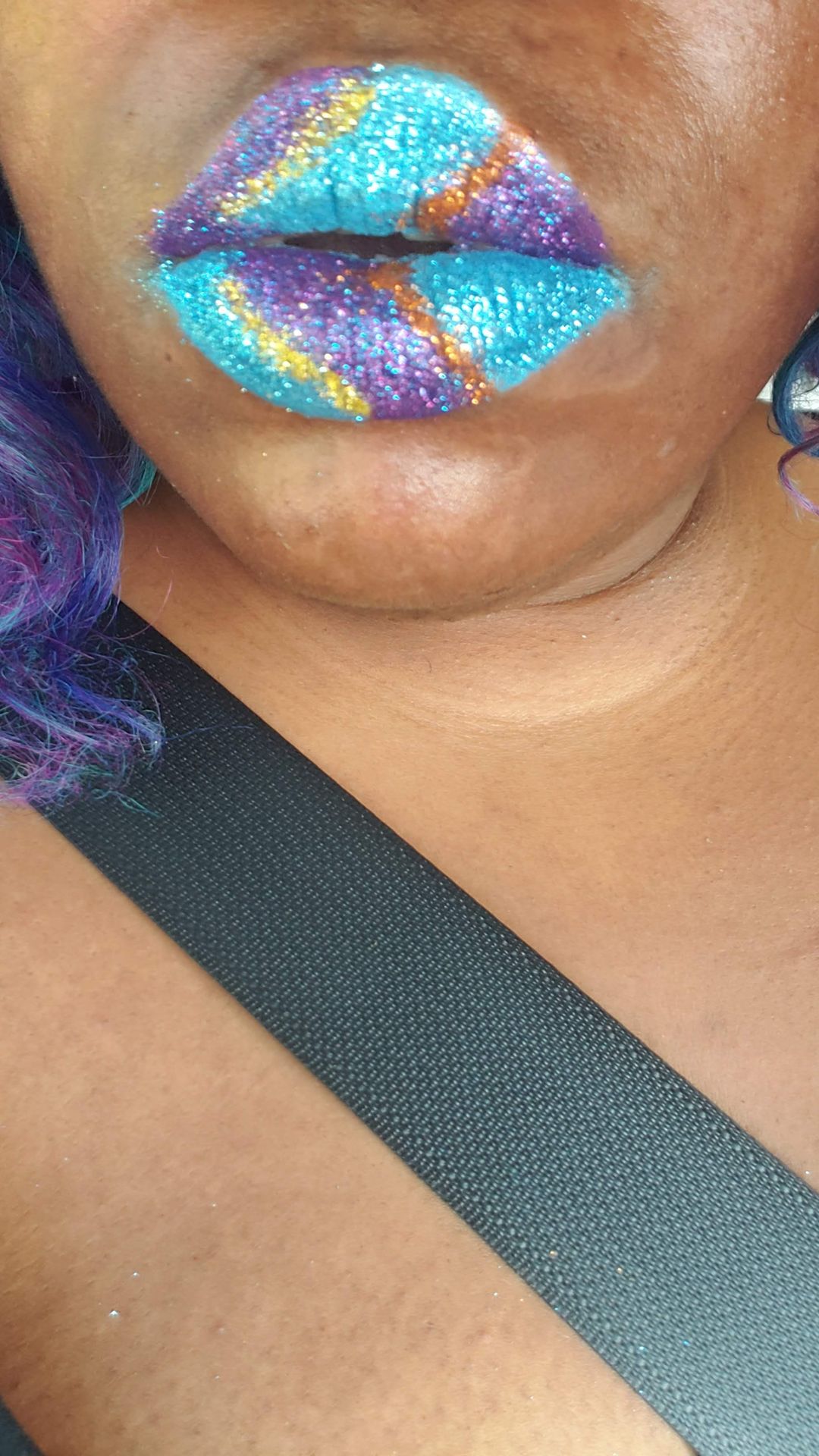 Close-up of teal and silver mosaic lip art near a black strap