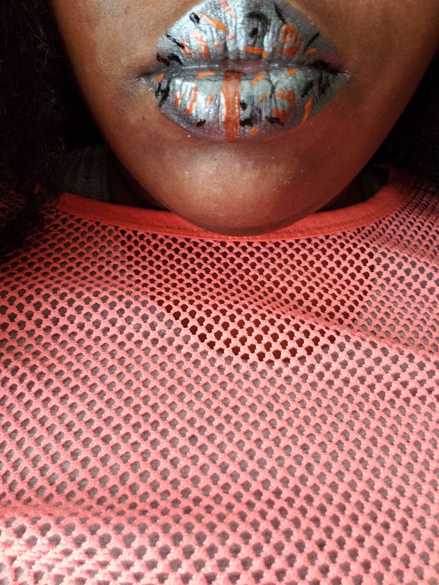 Close-up of navy blue shimmer lips above a coral sweater