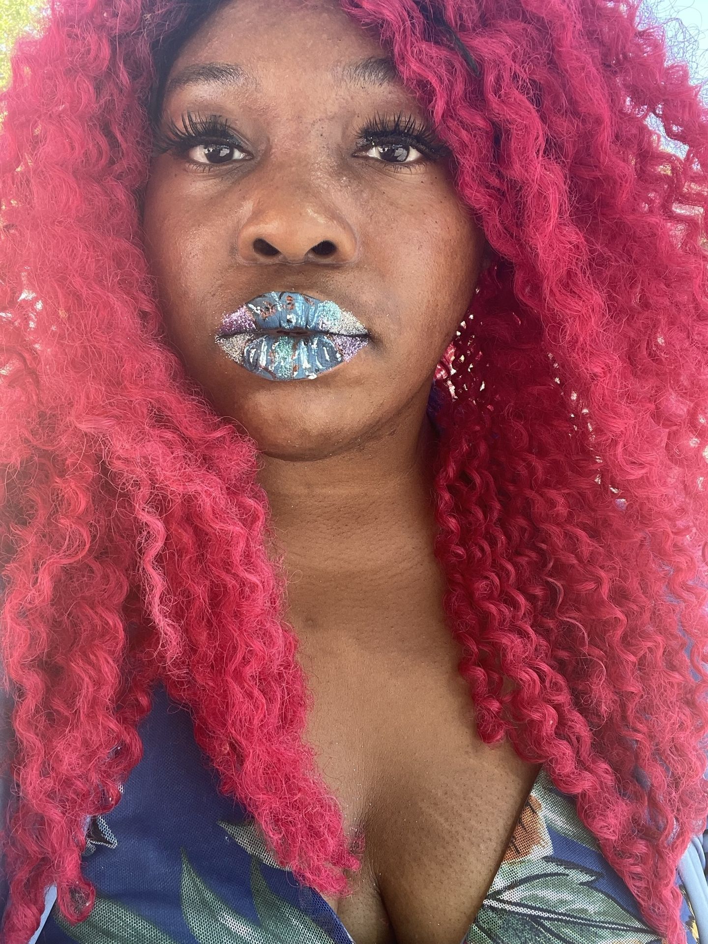 Black woman with deep red curls and icy blue metallic lipstick