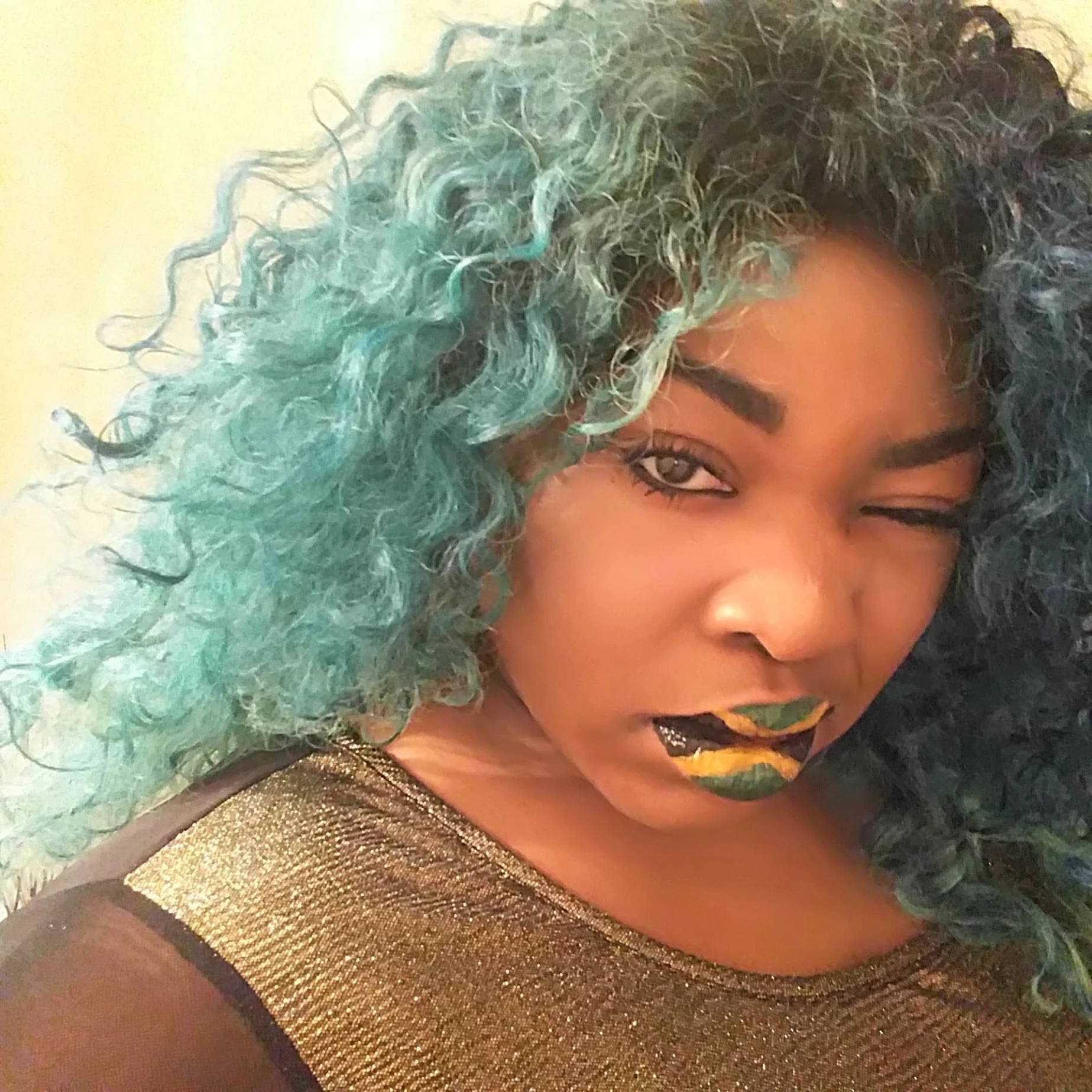 Black woman with teal curls and high-shine sapphire glitter lips