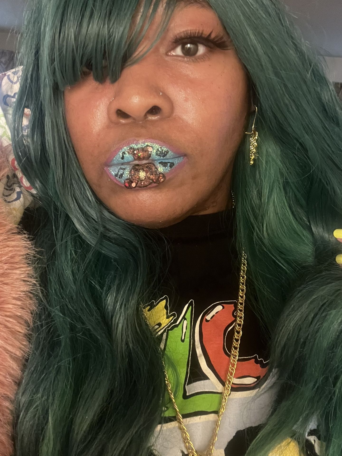 Woman with dark green hair and gold-flecked emerald lip design