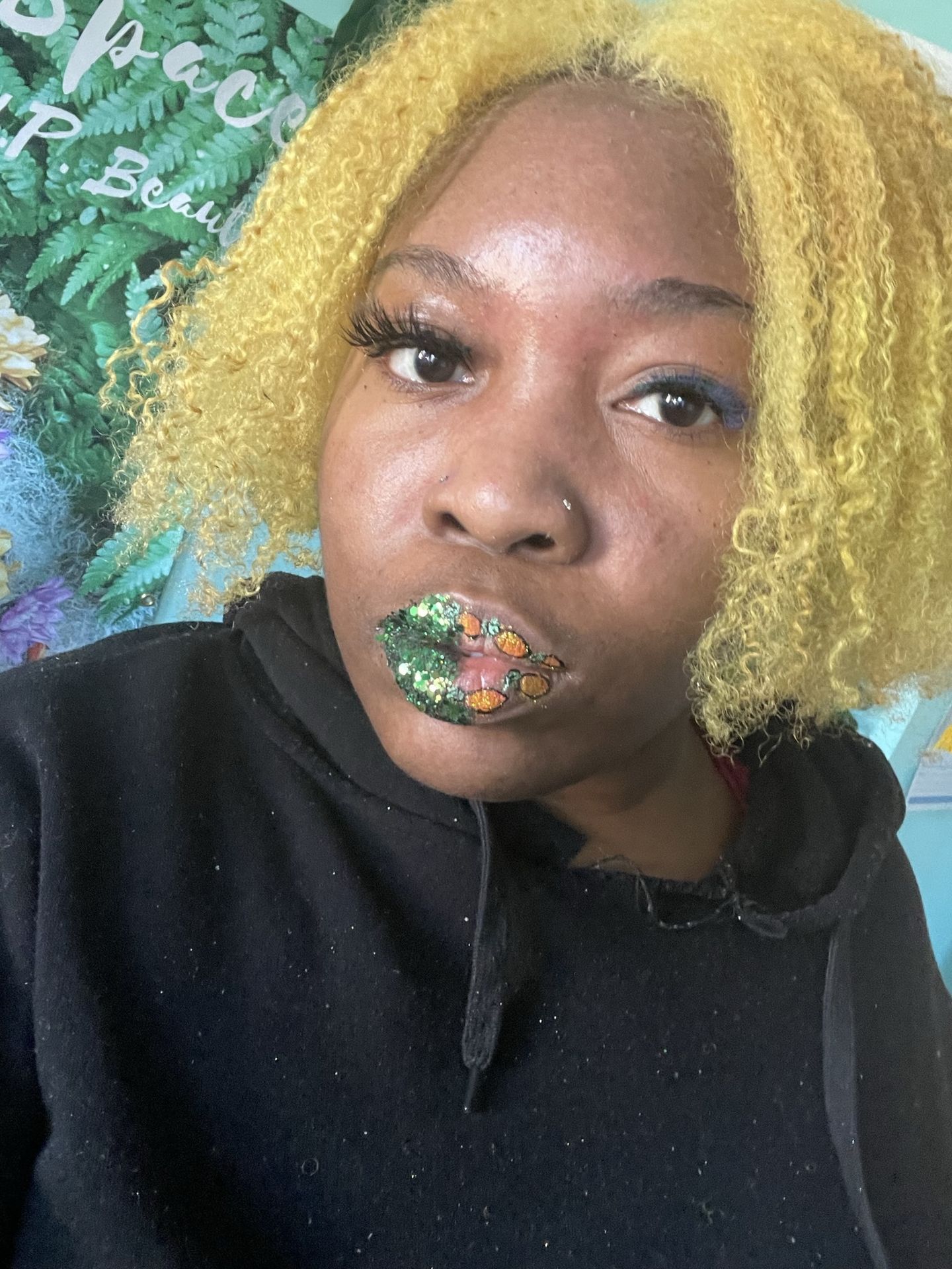 Woman with green-highlighted curls wearing moss-gold metallic lipstick