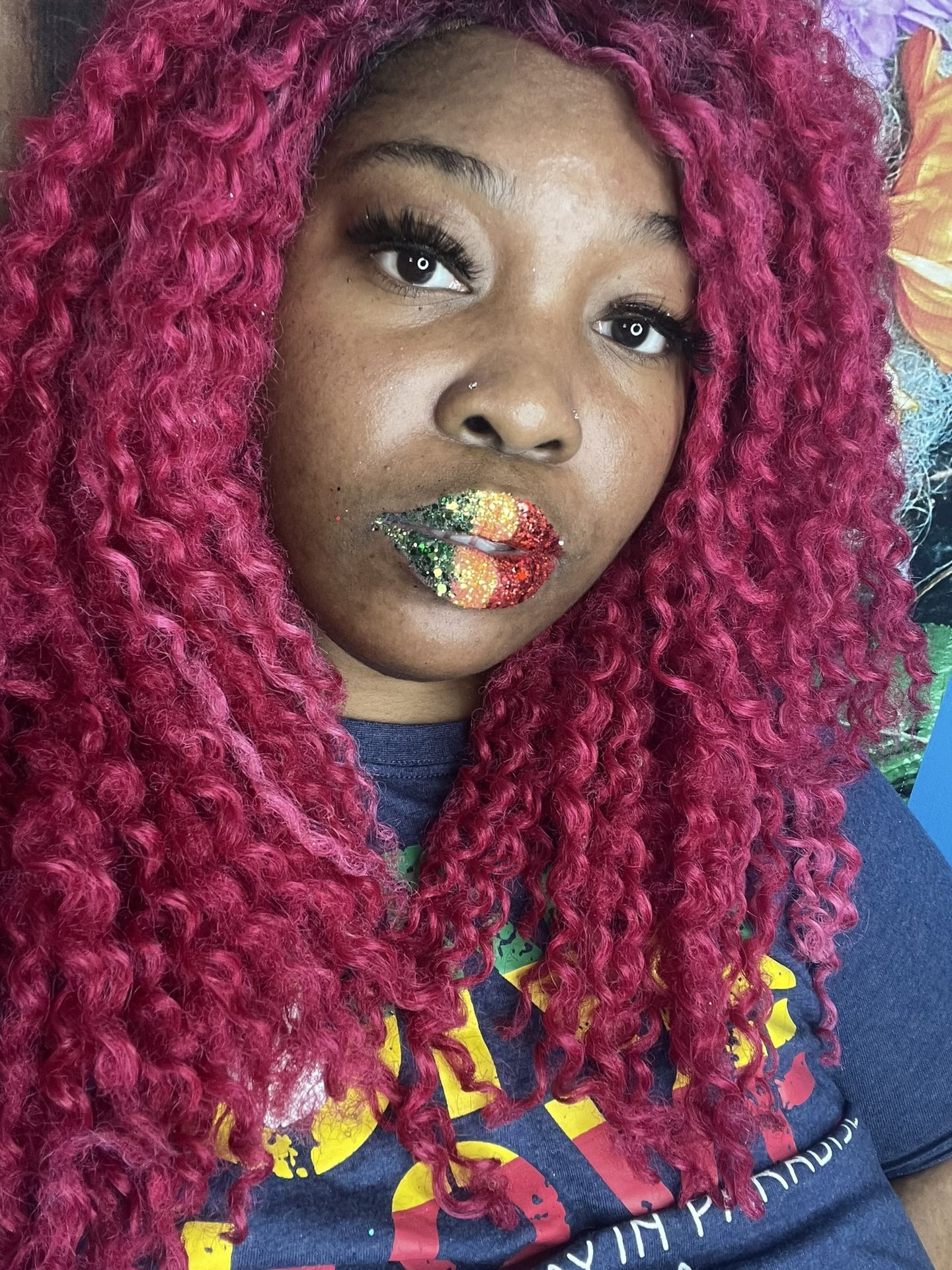 Black woman with crimson curls and green rhinestone lip pattern