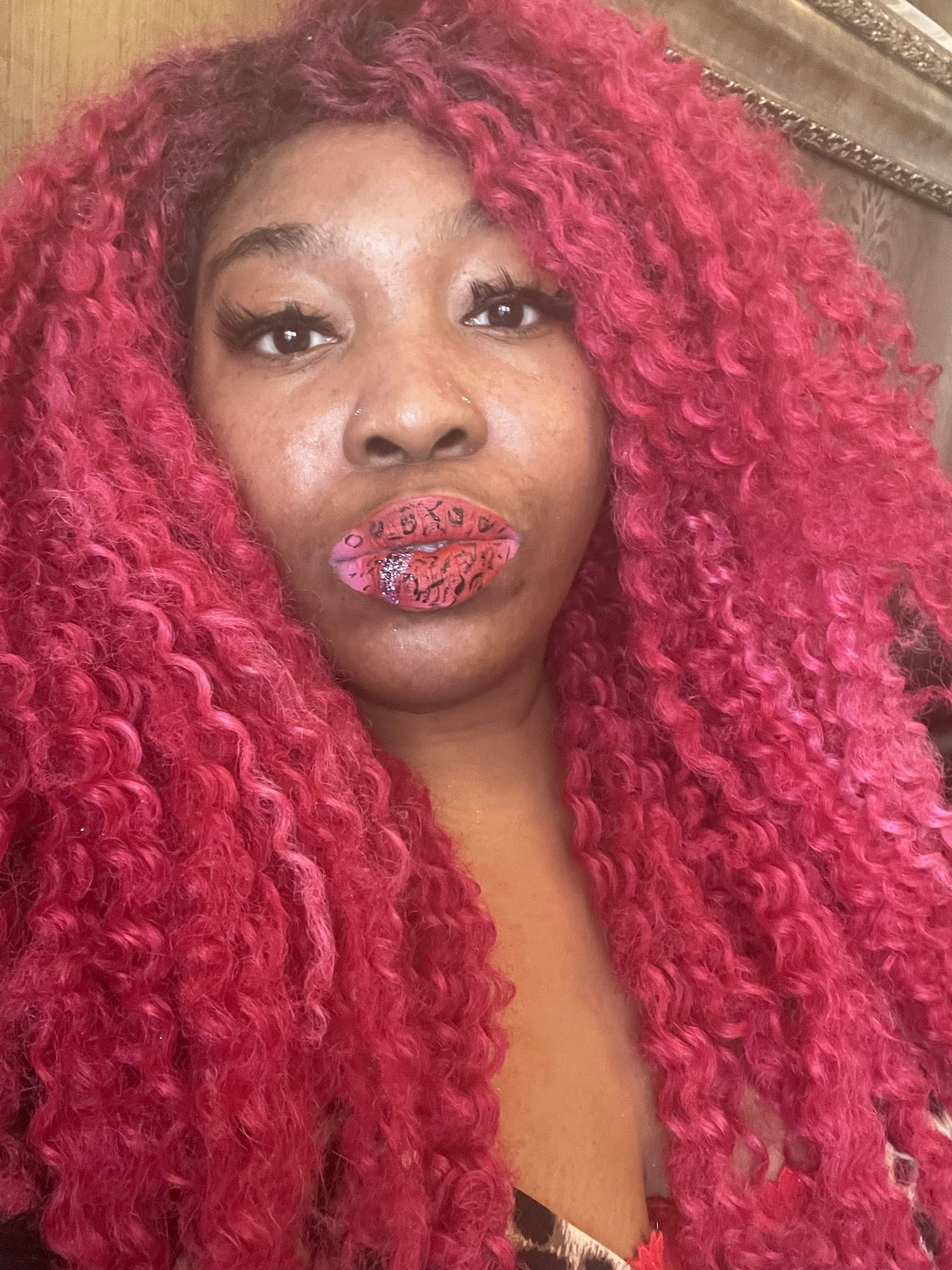 Woman with long crimson curls wearing glossy berry lipstick