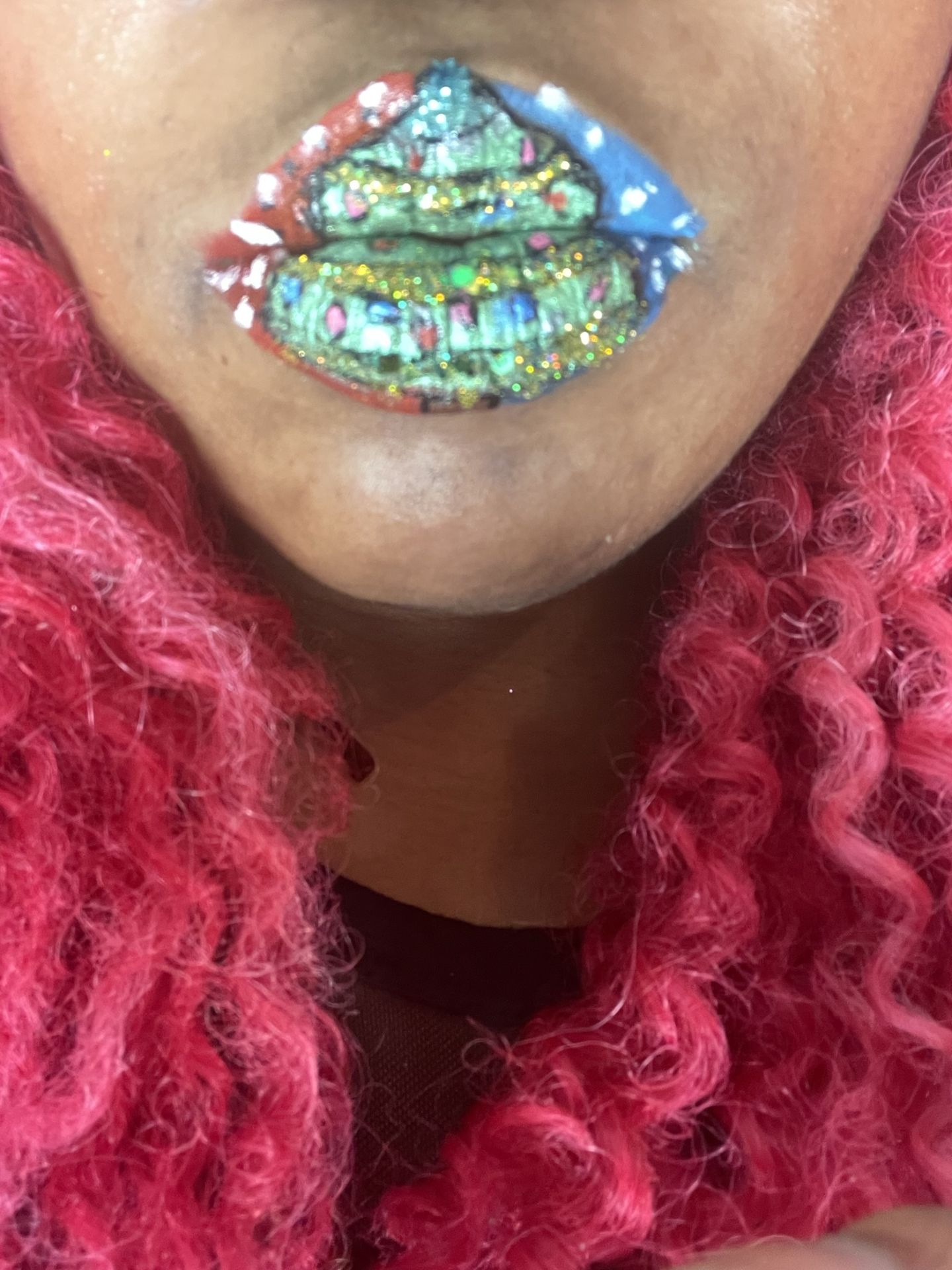 Close-up of emerald and gold mosaic lips framed by red curls