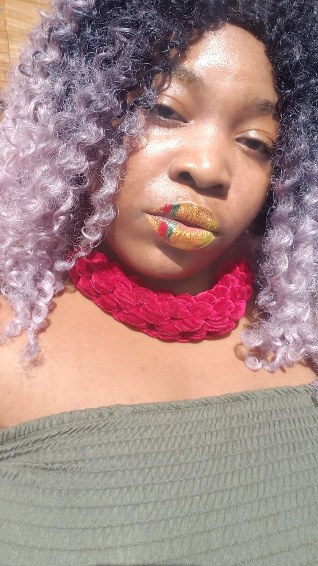 Woman with silver curls and a red choker wearing ruby gloss lips