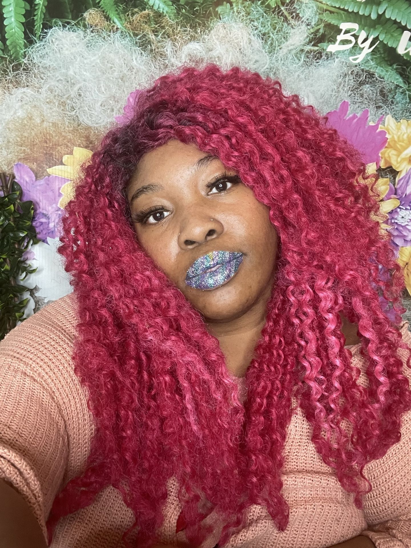 Black woman with bright red curls smiling with multicolor gem lips