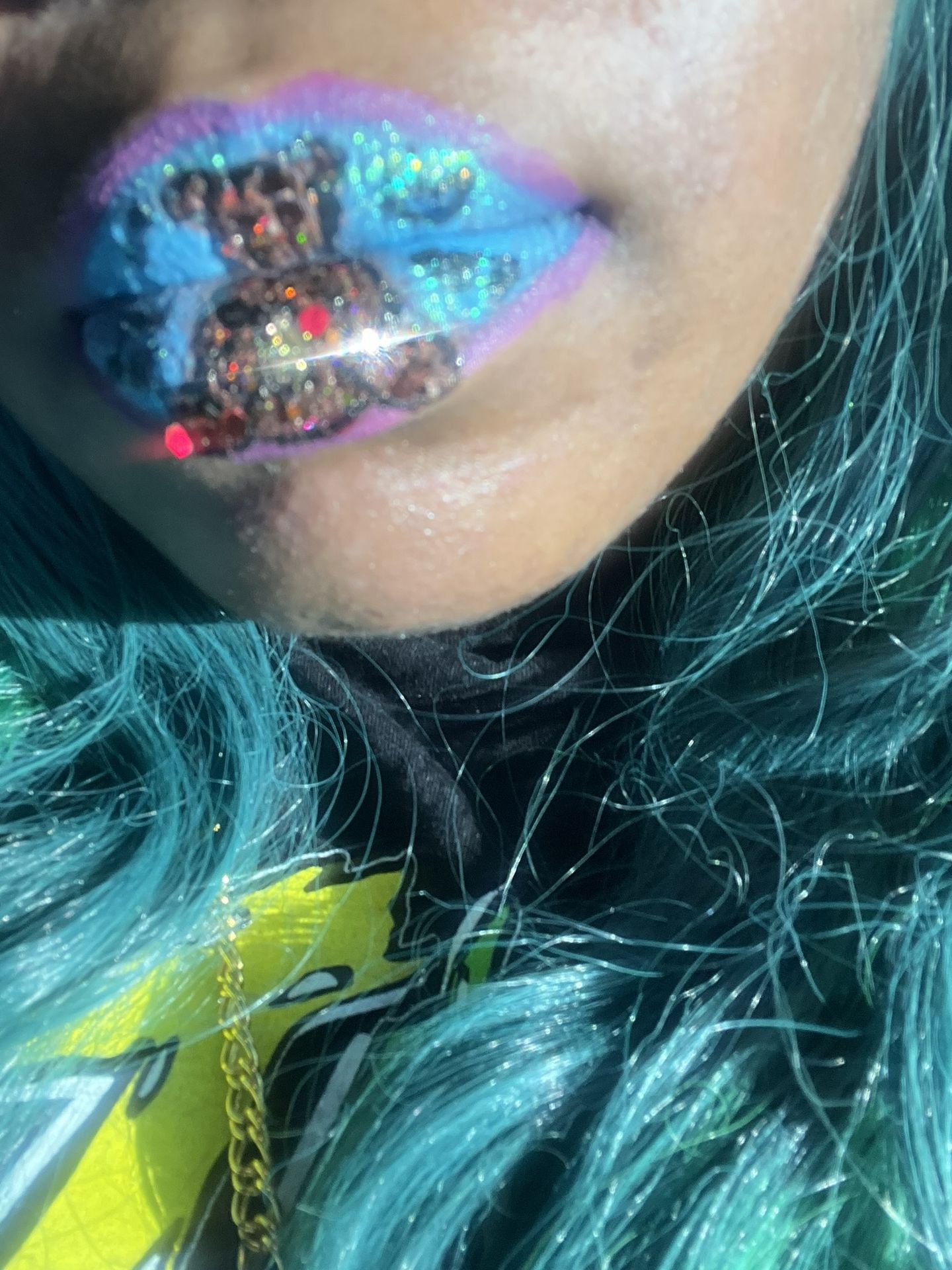 Close-up of turquoise and violet foil lips against dark curls