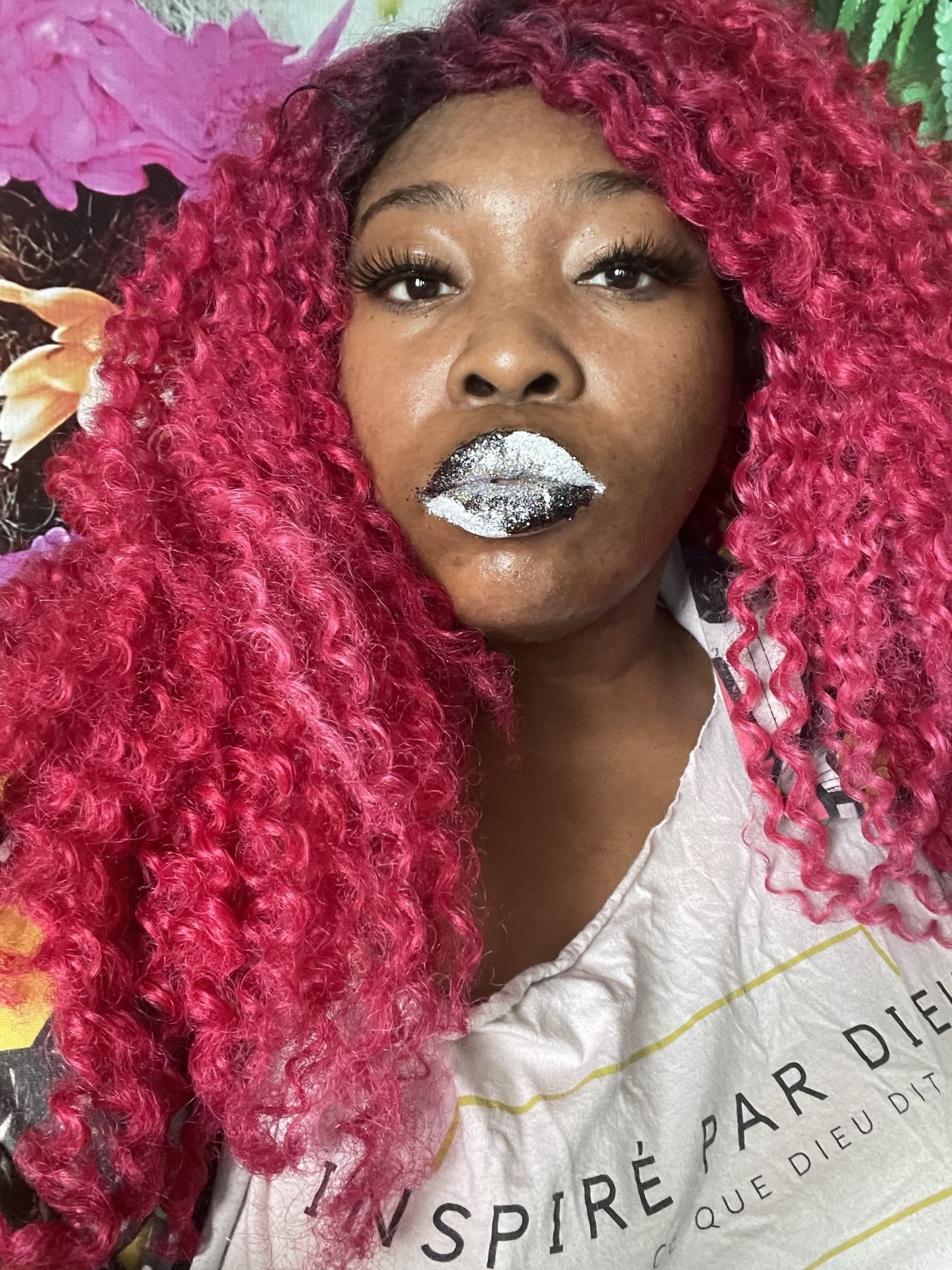 Woman with red curls and silver glitter lips against a floral background