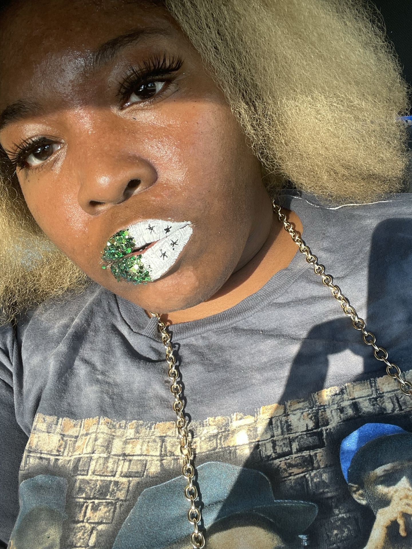 Black woman with blonde curls and green crystal lip accents