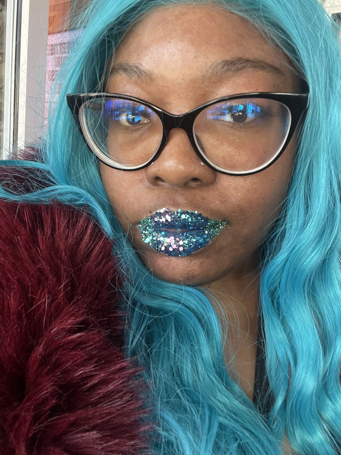Woman with glasses and aqua hair wearing deep blue metallic lipstick