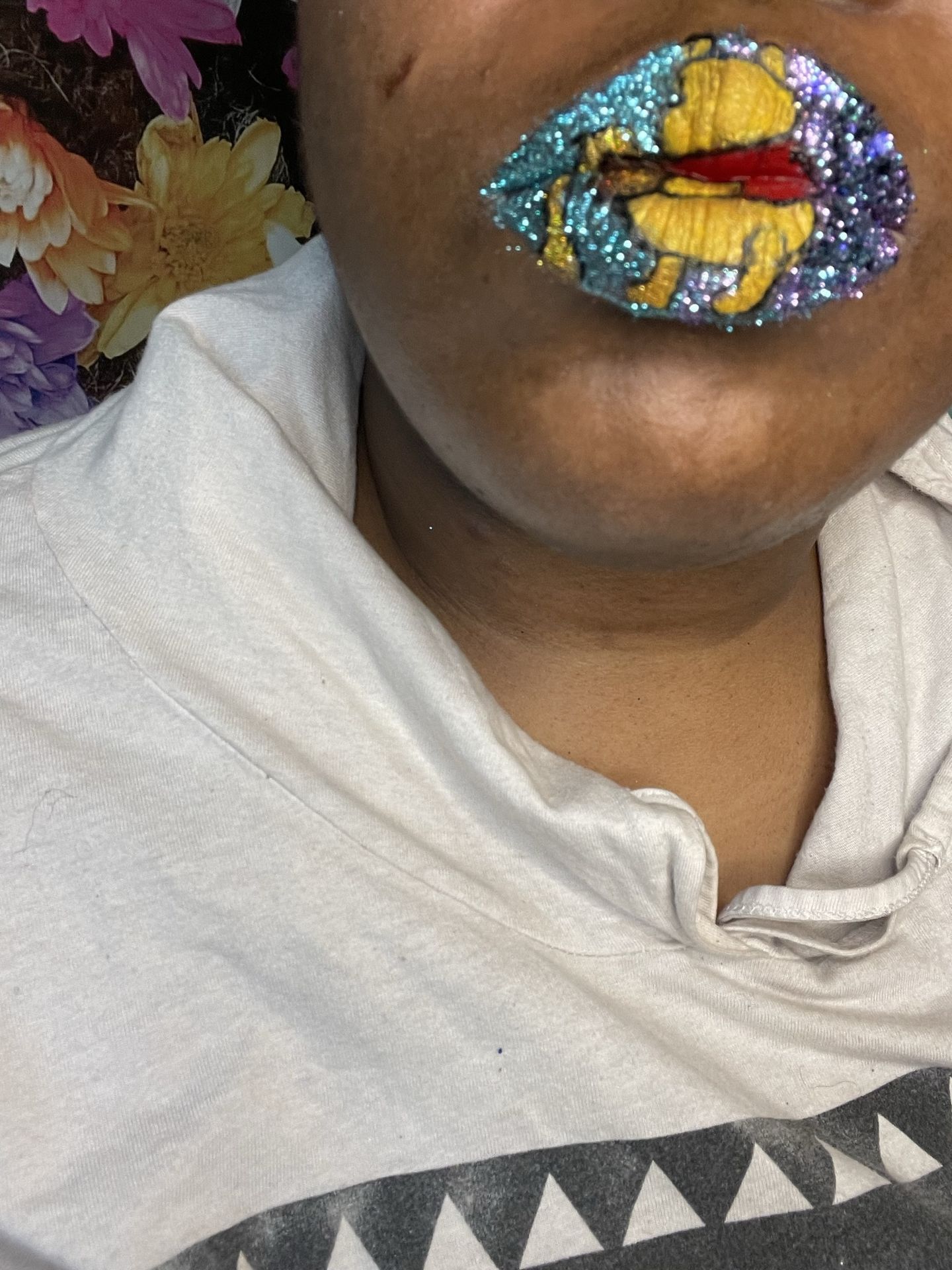 Close-up of turquoise glitter lipstick above a beige hoodie