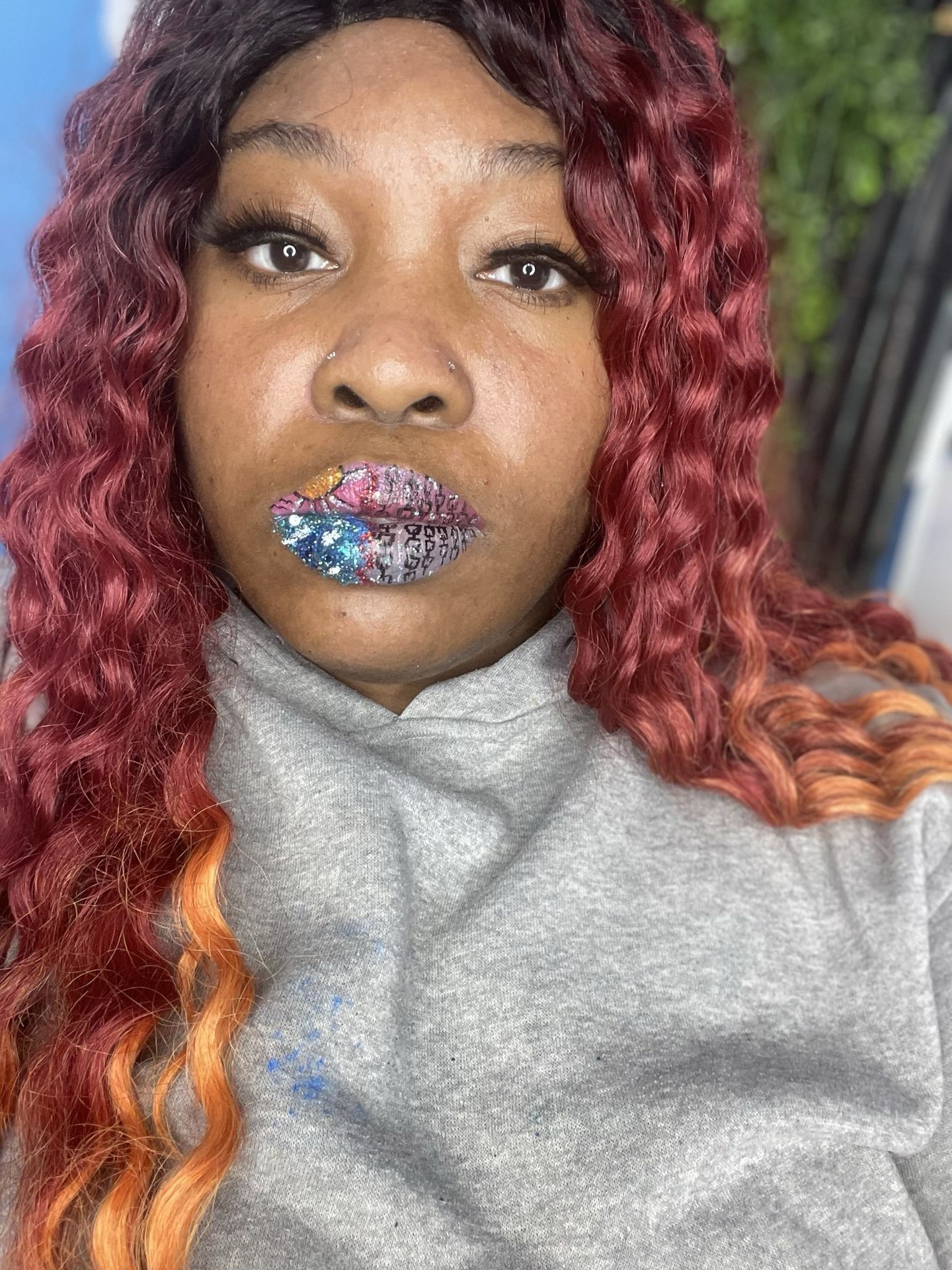 Woman with red and blonde ombré curls wearing sapphire shimmer lips