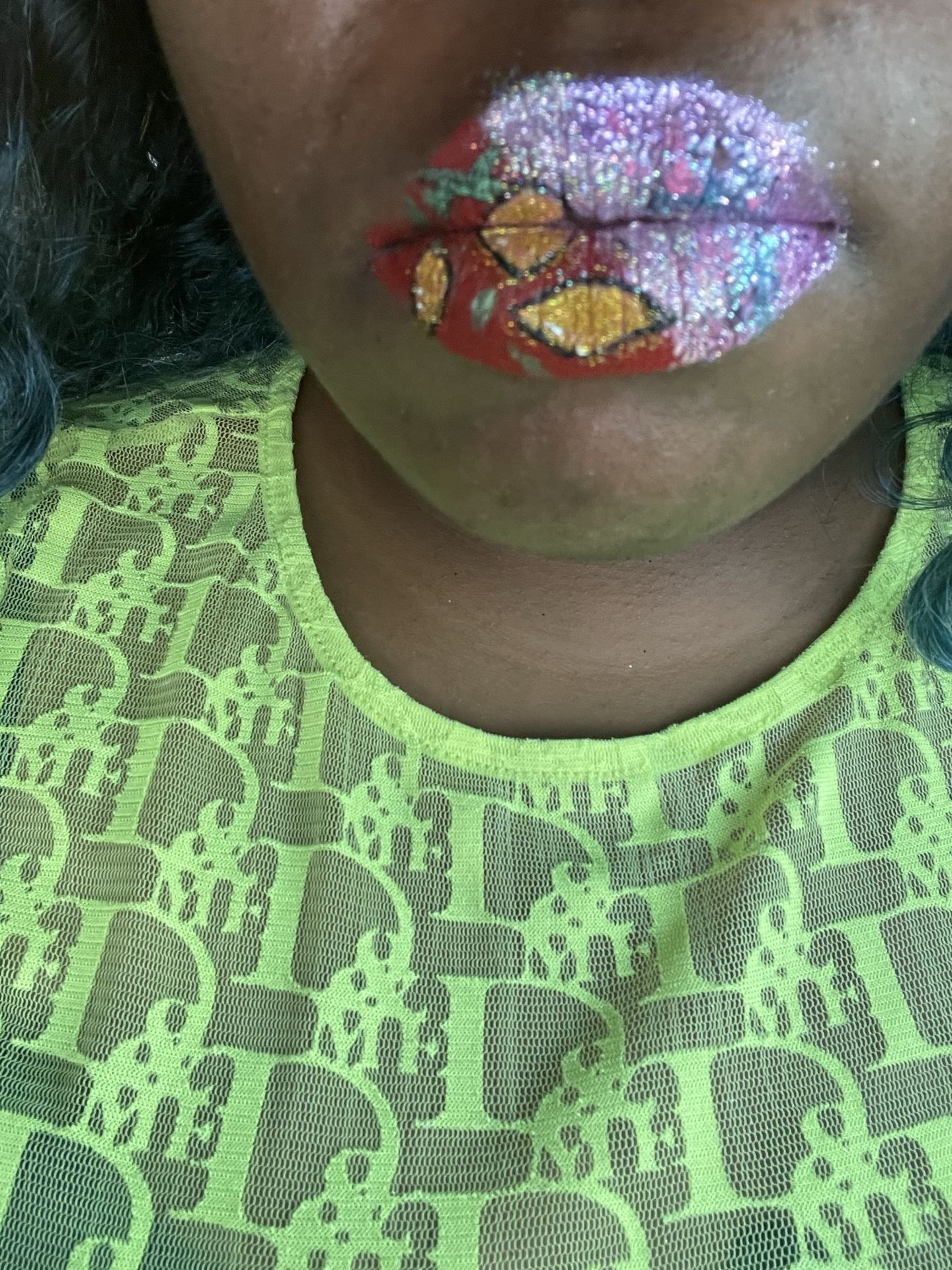 Close-up of multicolor jewel lip art against a lime green top