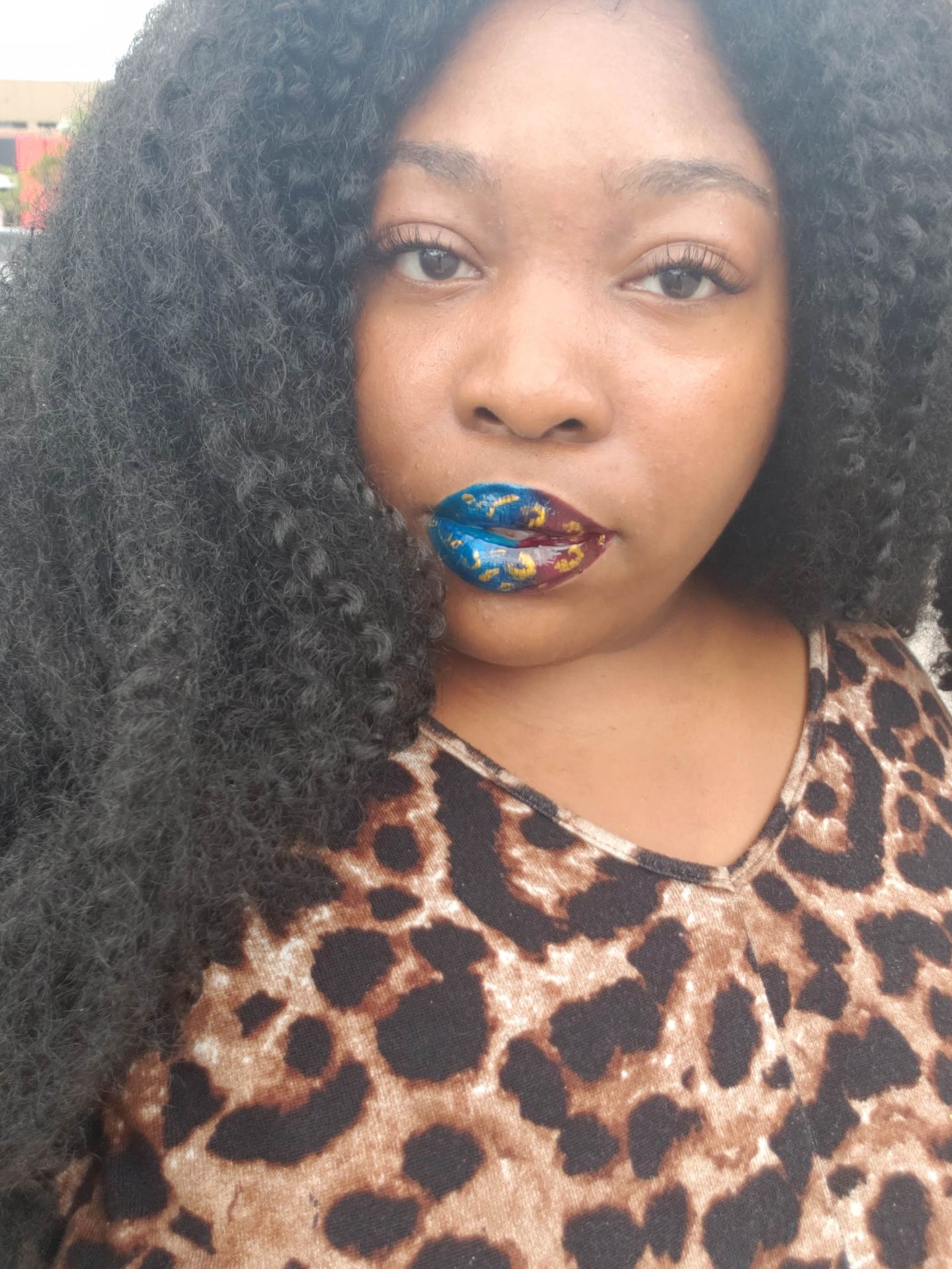 Woman in leopard print top wearing blue-green glitter lipstick