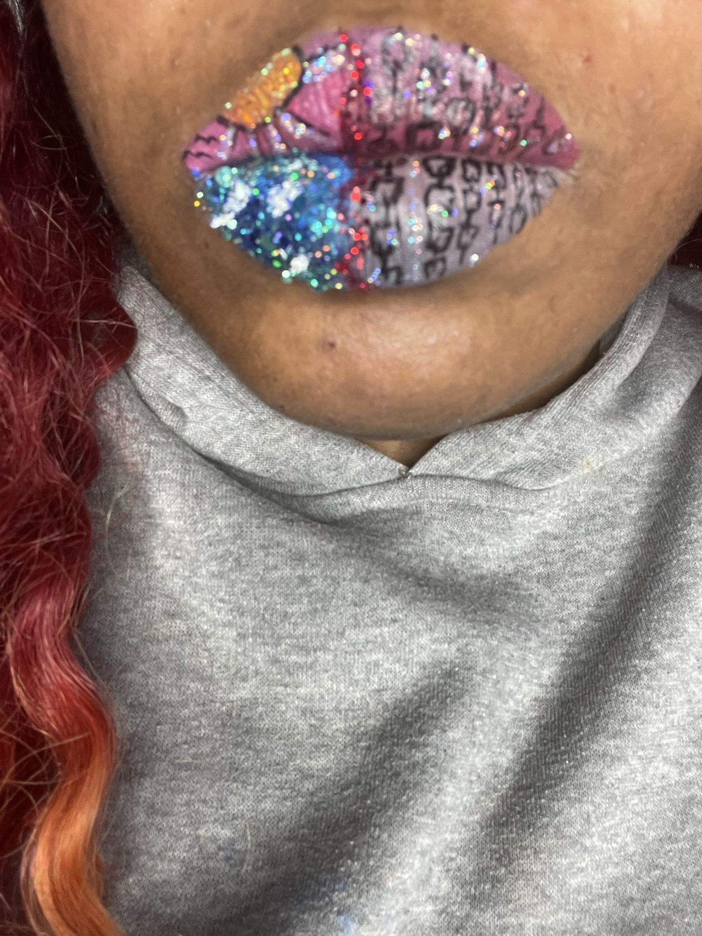 Close-up of multicolored gemstone lips against a gray sweater