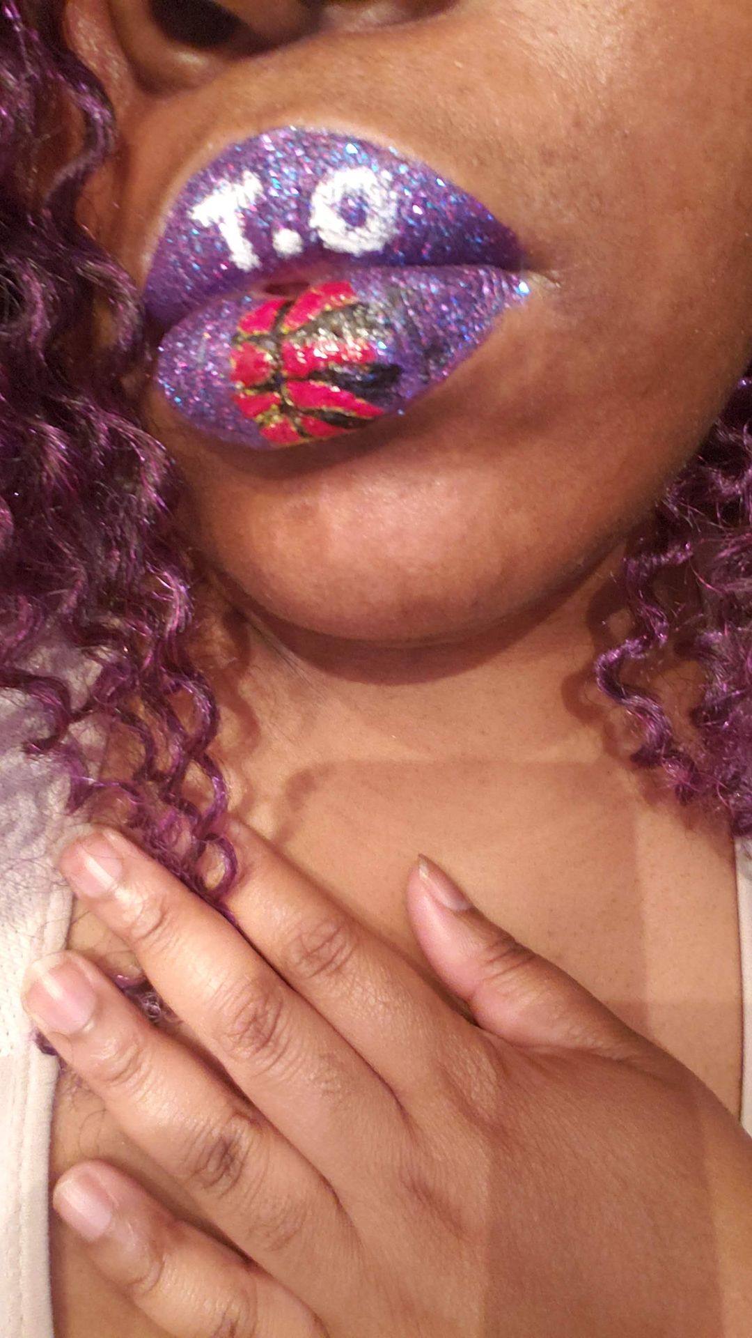 Close-up of red and gold rhinestone lips with hands at collarbone