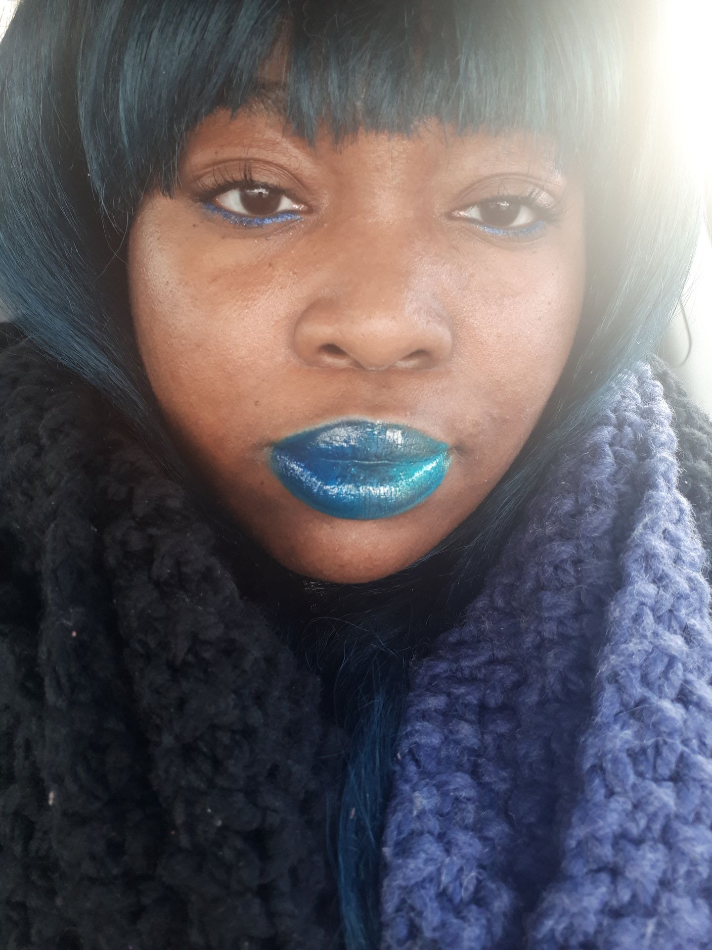 Black woman with long dark curls and teal satin lipstick