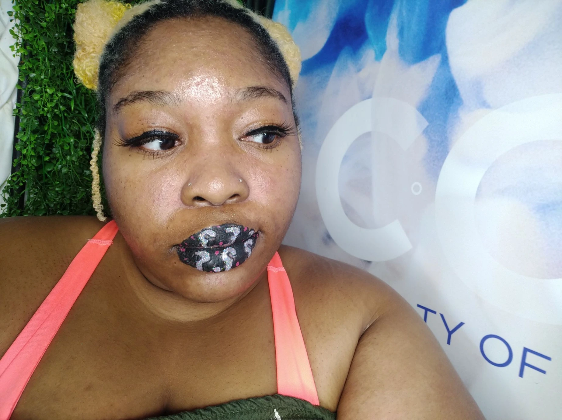 Woman in coral top wearing sapphire glitter lips against a blue background
