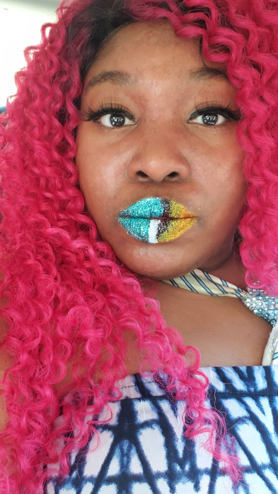 Black woman with deep red curly hair wearing green and gold glitter lip art, close-up creative beauty portrait with bold texture and shine.