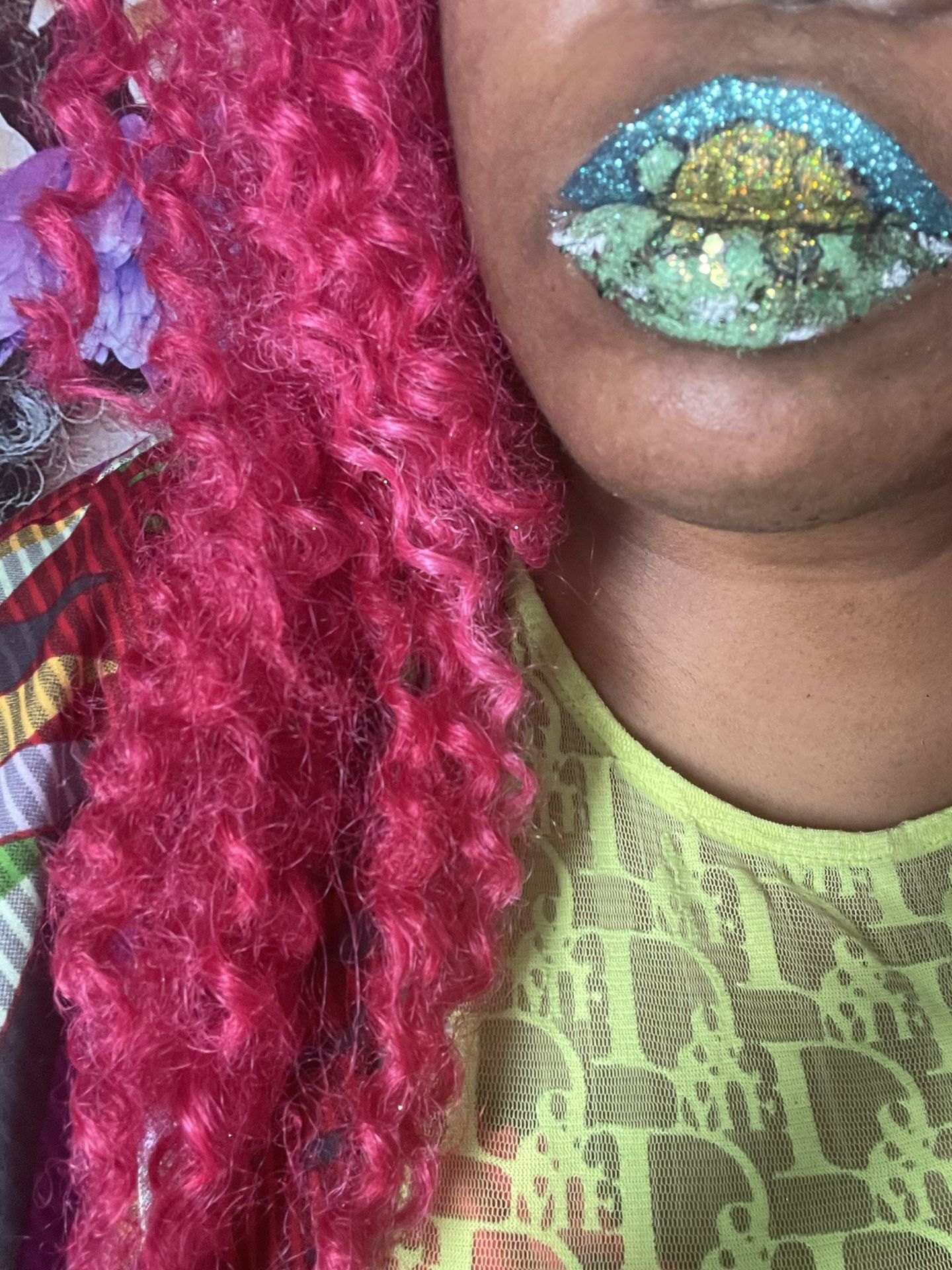 Close-up of green and gold glitter lips beside red curls