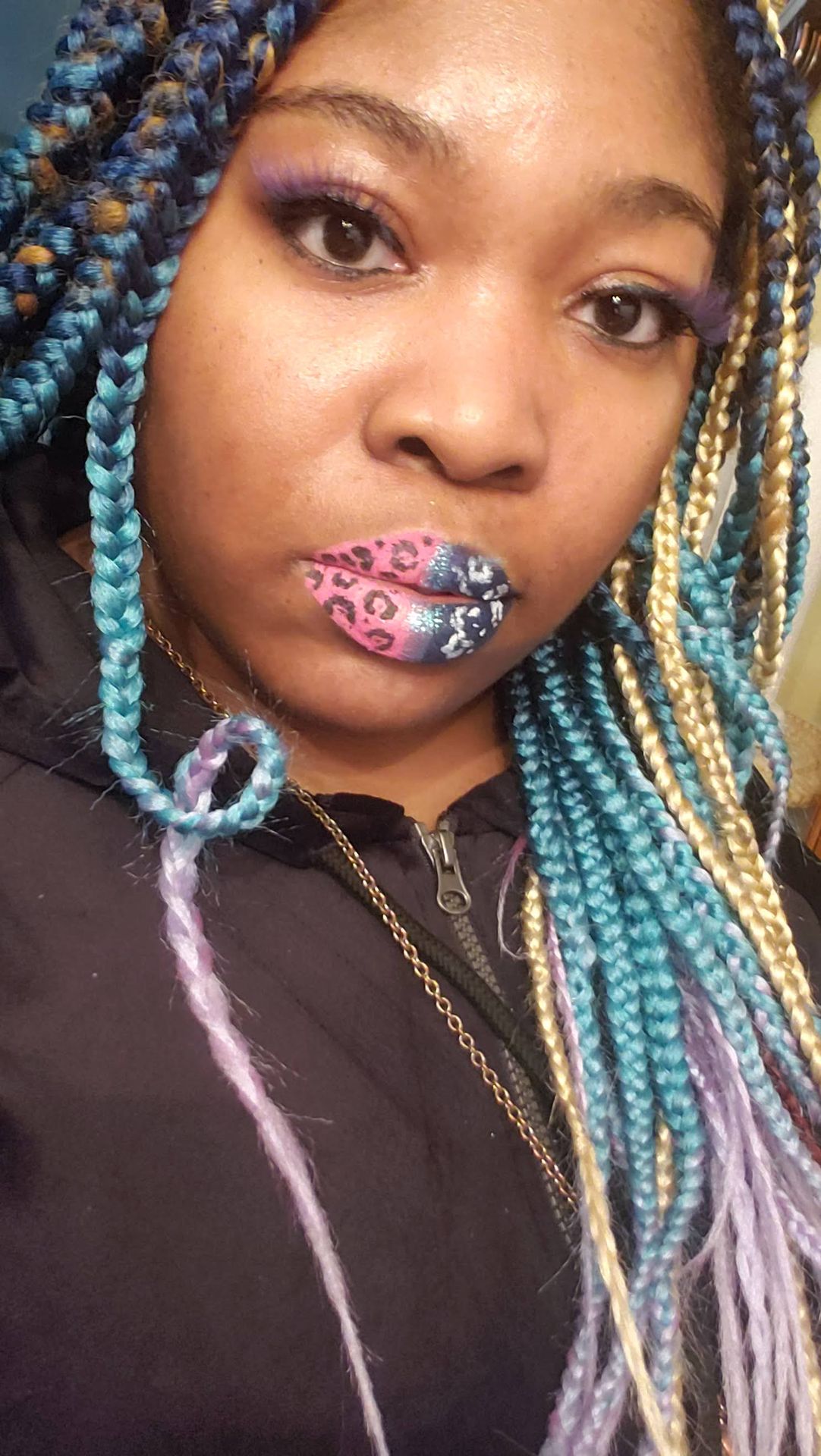 Black woman with red braids and emerald crystal lip art, luxury-inspired beauty portrait.