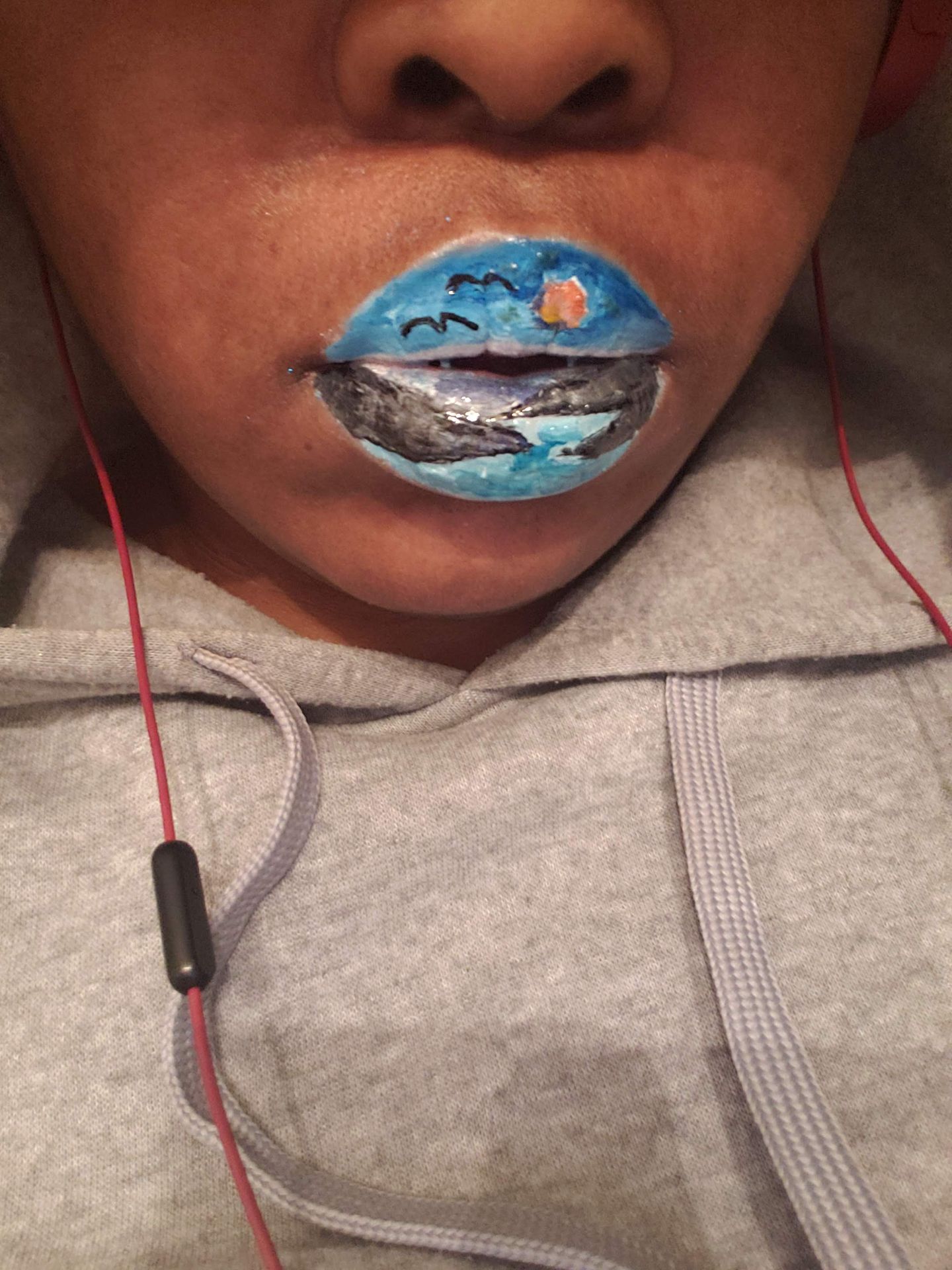 Black woman wearing a gray hoodie and blue metallic lipstick