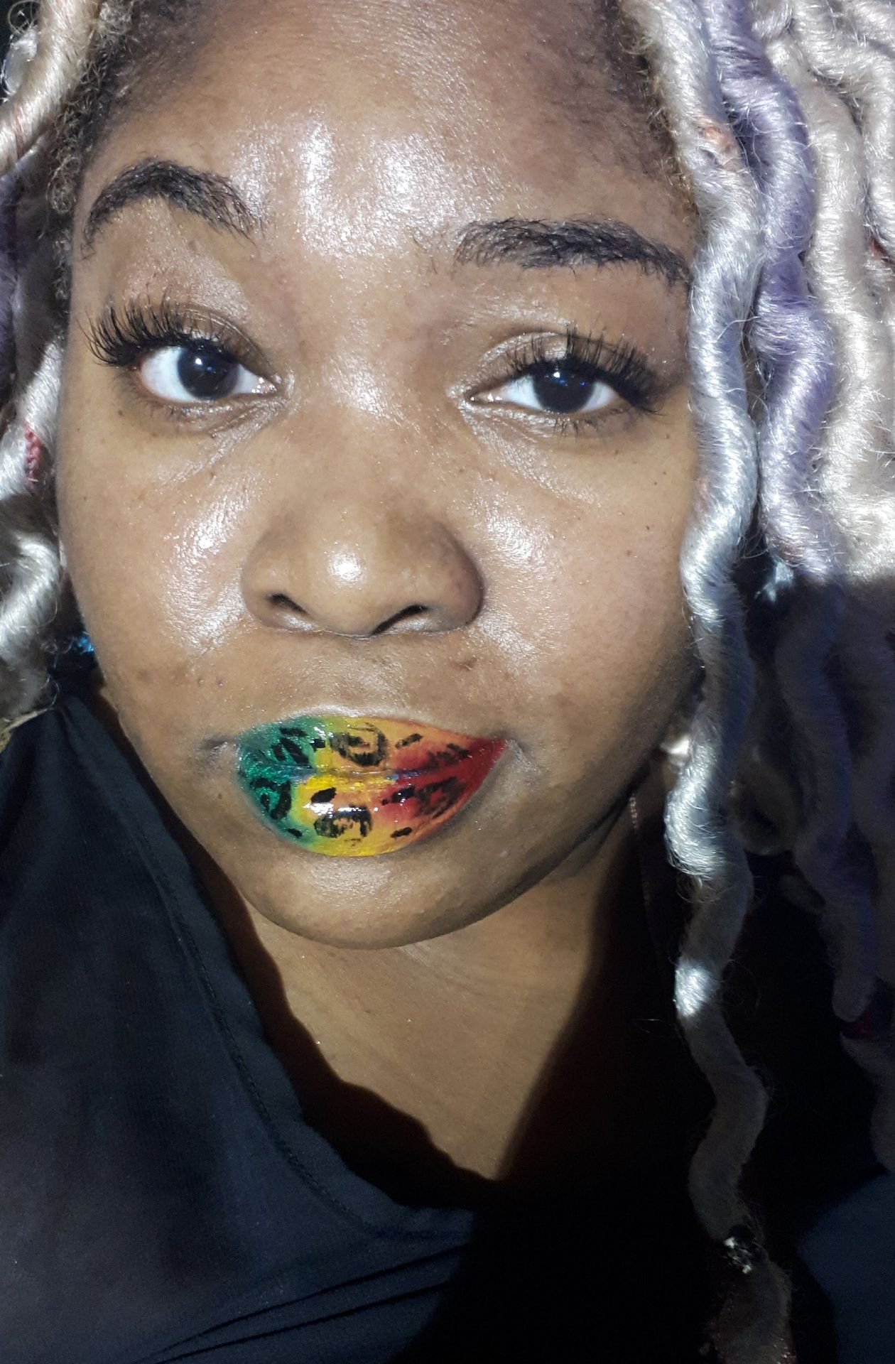 Black woman with soft grey curls and multicolor sparkle lips, close-up portrait highlighting shimmer and depth.