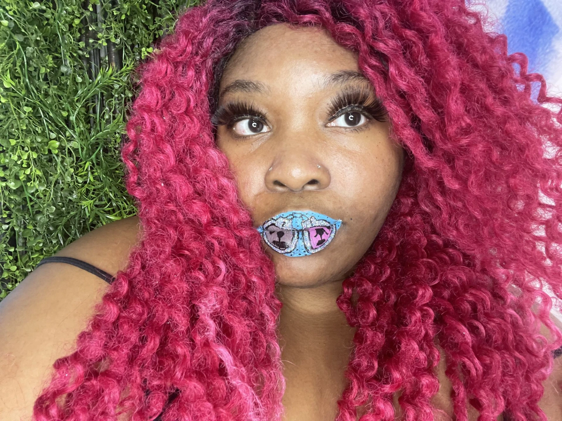 Woman with deep red curls and emerald metallic lip finish