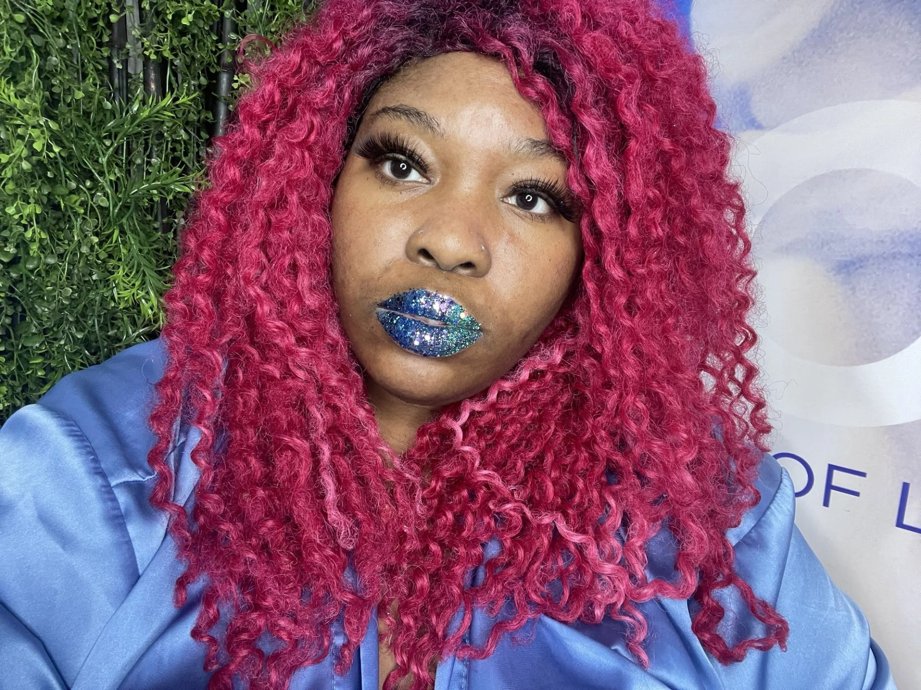 Woman with crimson curls wearing ocean-blue satin lipstick