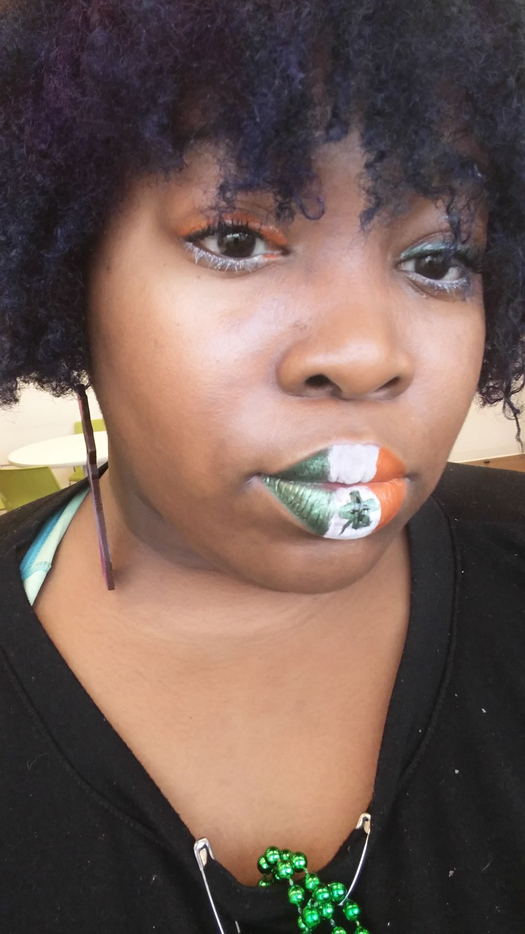 Woman with short black curls wearing emerald and white crystal lip art