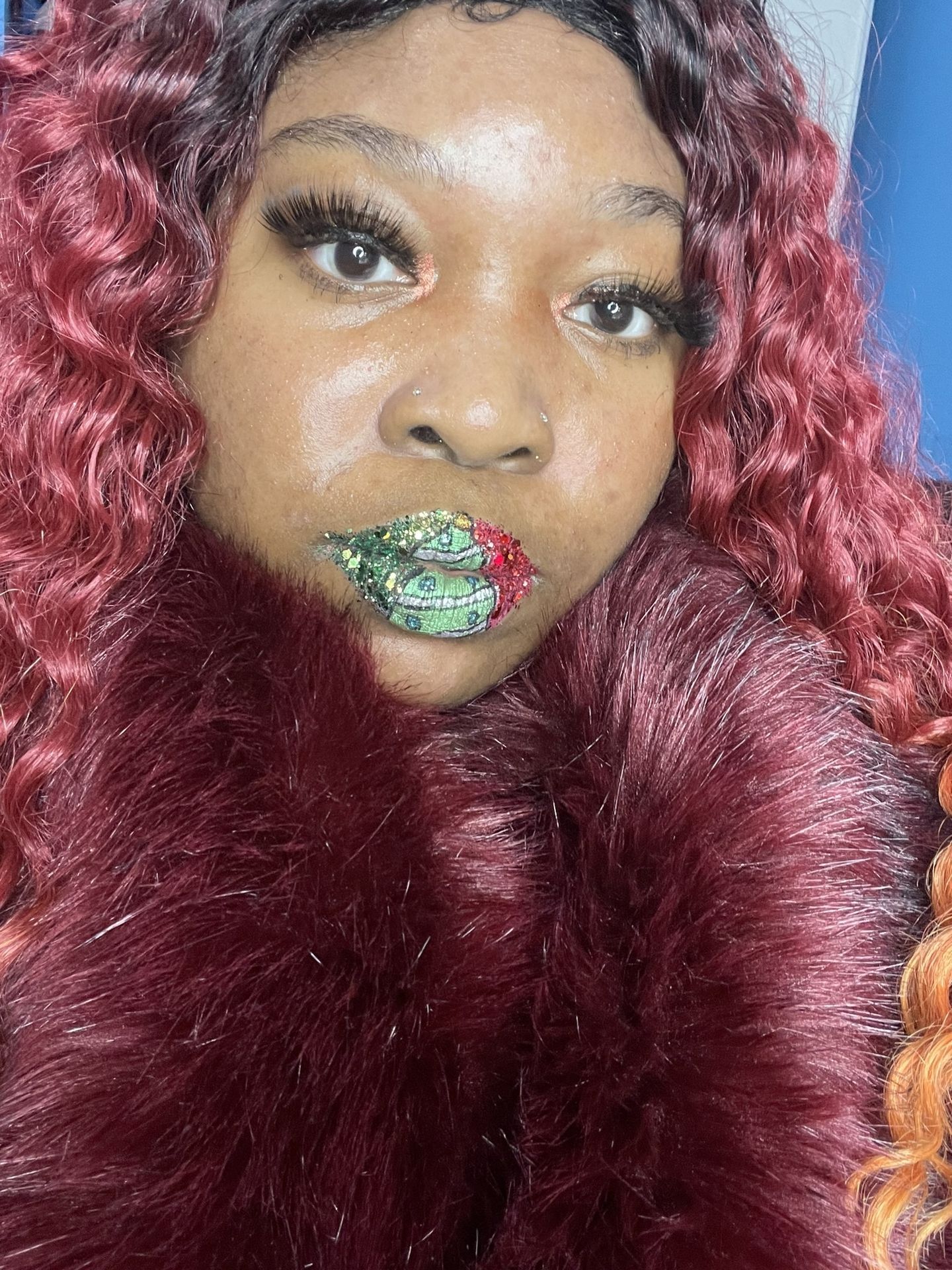 Woman with deep red curls and emerald rhinestone lip design