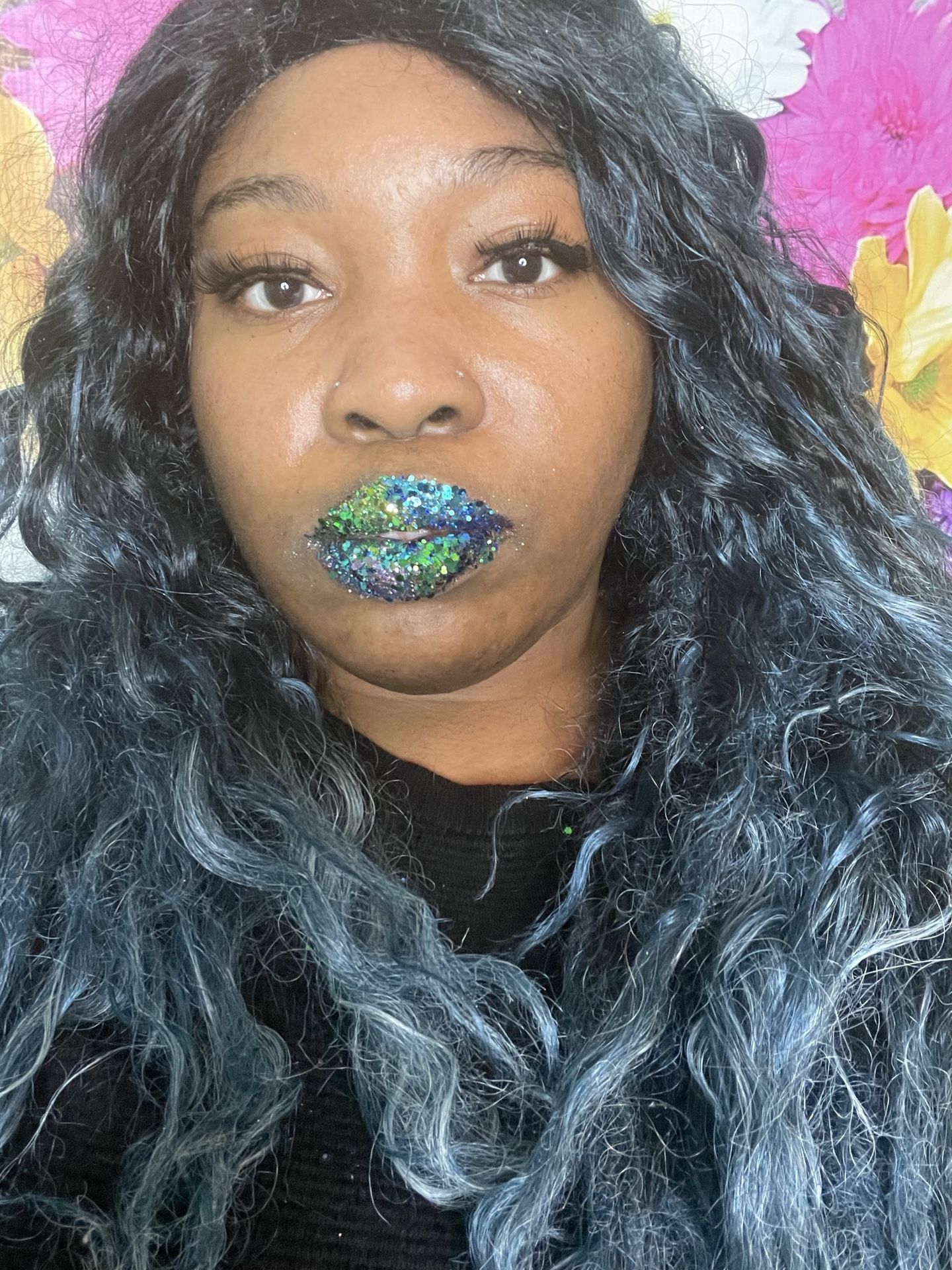 Black woman with blue-toned hair wearing emerald shimmer lipstick